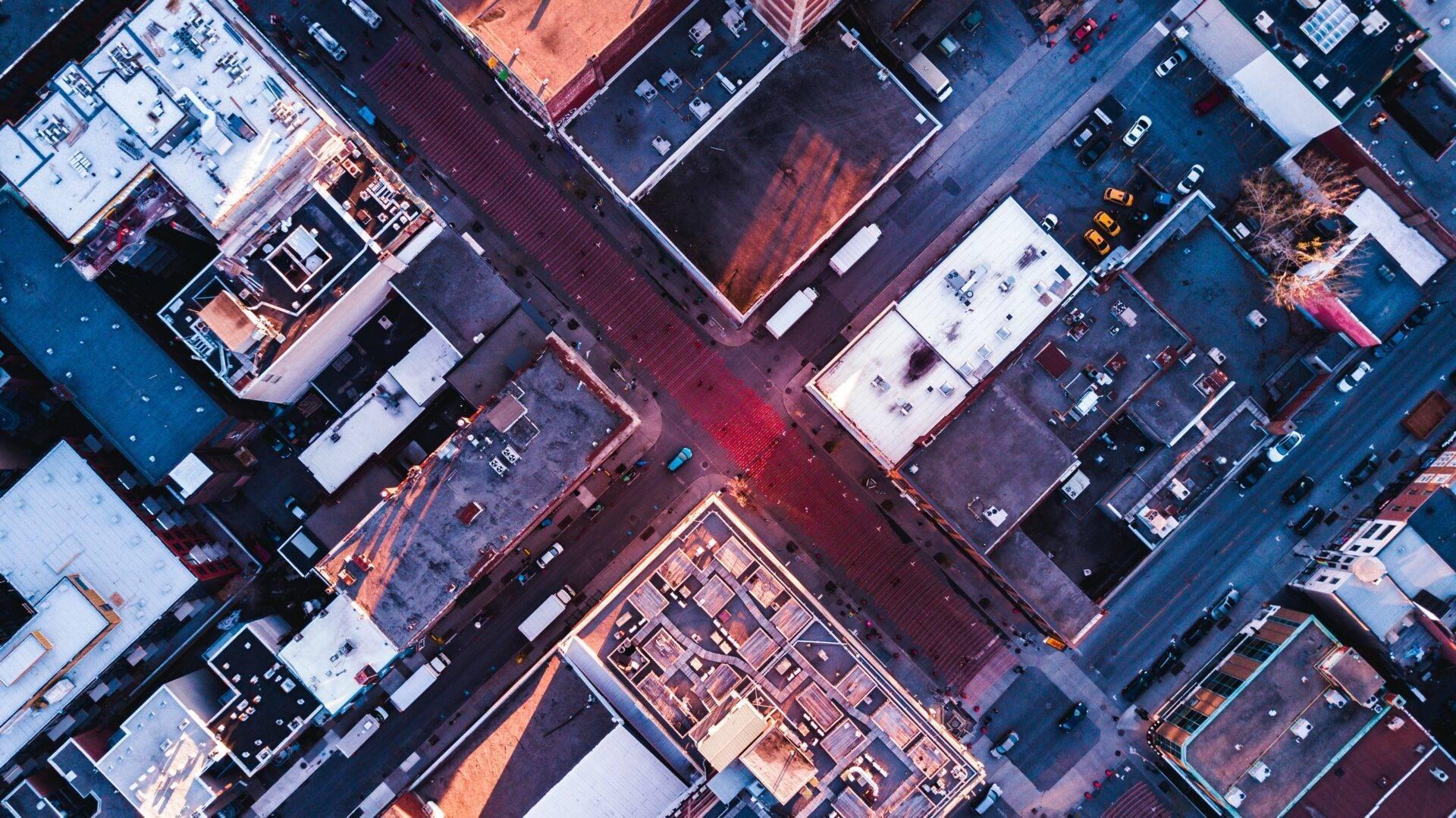 Vue aérienne d’un quartier urbain densément construit avec immeubles, toits colorés et rues entrecroisées