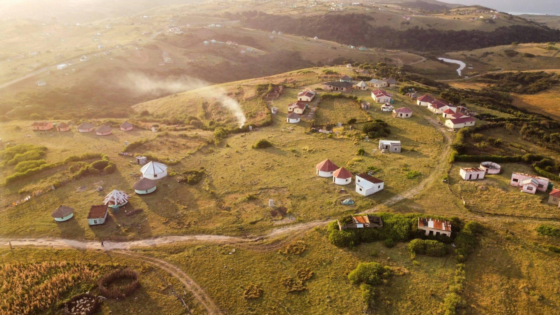 Vista aerea di un villaggio con case dai tetti rossi sparse in un paesaggio verde e collinare