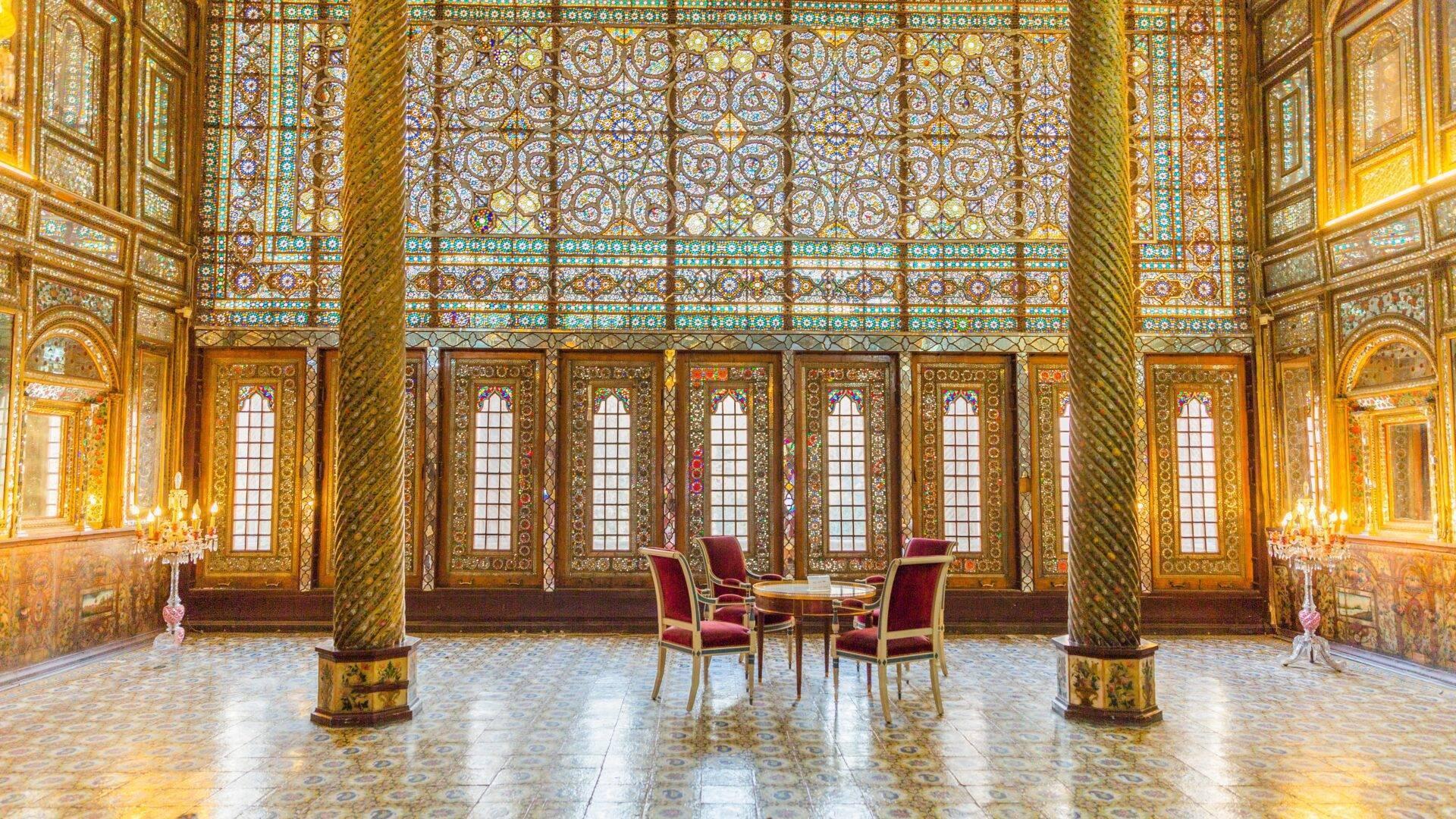 Salle ornée de dorures et mosaïques turquoises avec colonnes dorées et chaises rouges