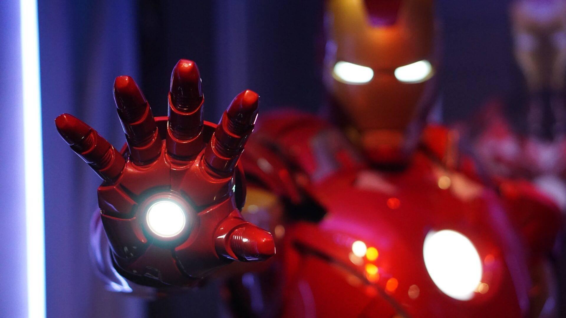 Figurine de super-héros en costume rouge avec gantelet luminescent dans une exposition ou musée