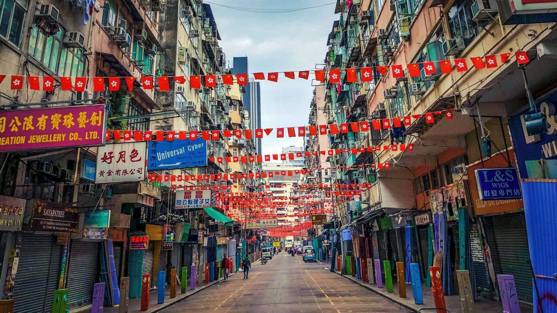 Une rue commerçante asiatique décorée de drapeaux rouges et blancs, bordée de petits commerces colorés