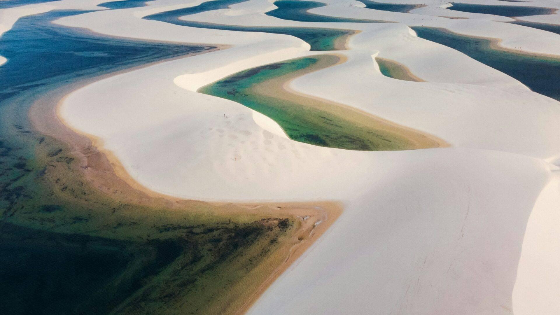 Luftaufnahme türkisfarbener Seen und weißer Sanddünen, die eine surreale Wüstenlandschaft bilden