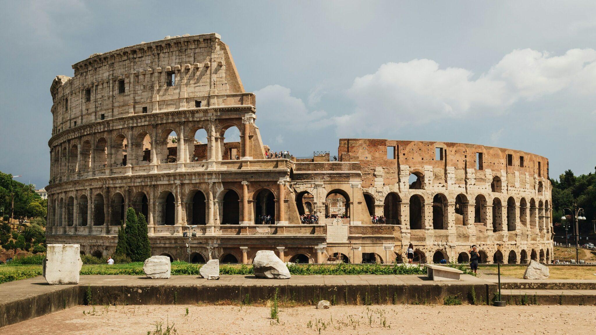 Les ruines majestueuses du Colisée antique à Rome avec ses arcades et gradins partiellement conservés sous un ciel bleu