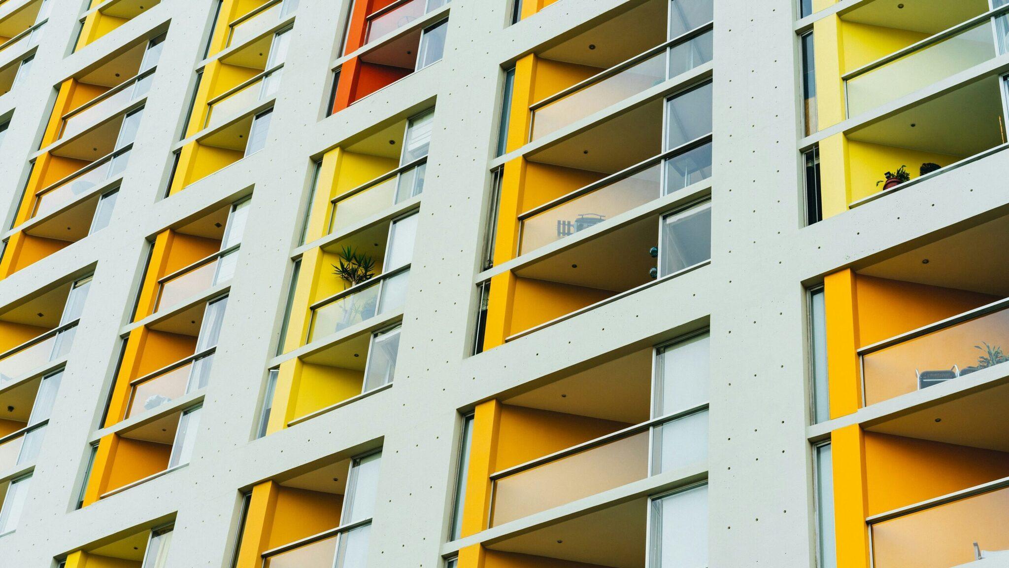 Façade moderne d’un immeuble résidentiel aux balcons jaunes et blancs typique de l’architecture urbaine contemporaine