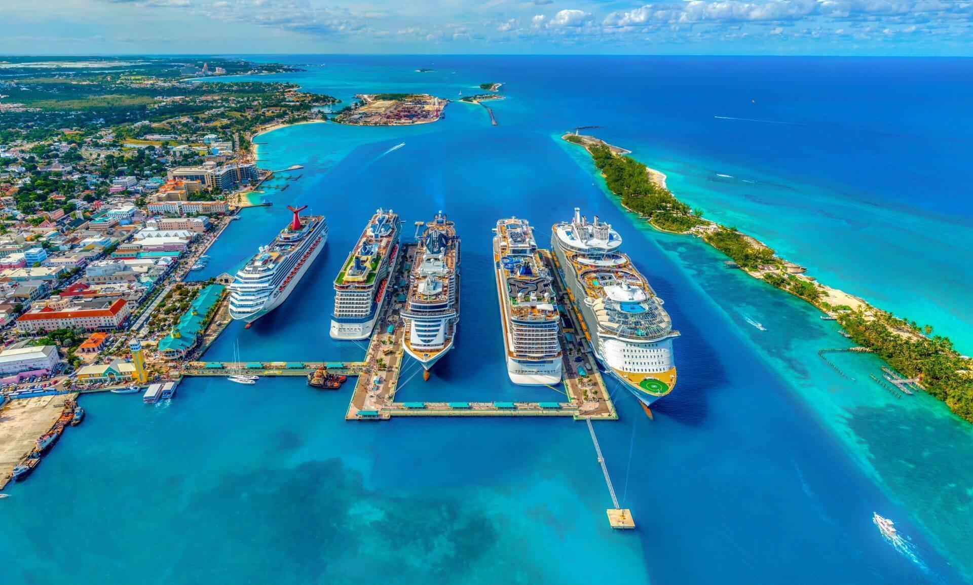 Vista aérea de un puerto de cruceros tropical con seis barcos amarrados en una bahía turquesa rodeada de islotes verdes