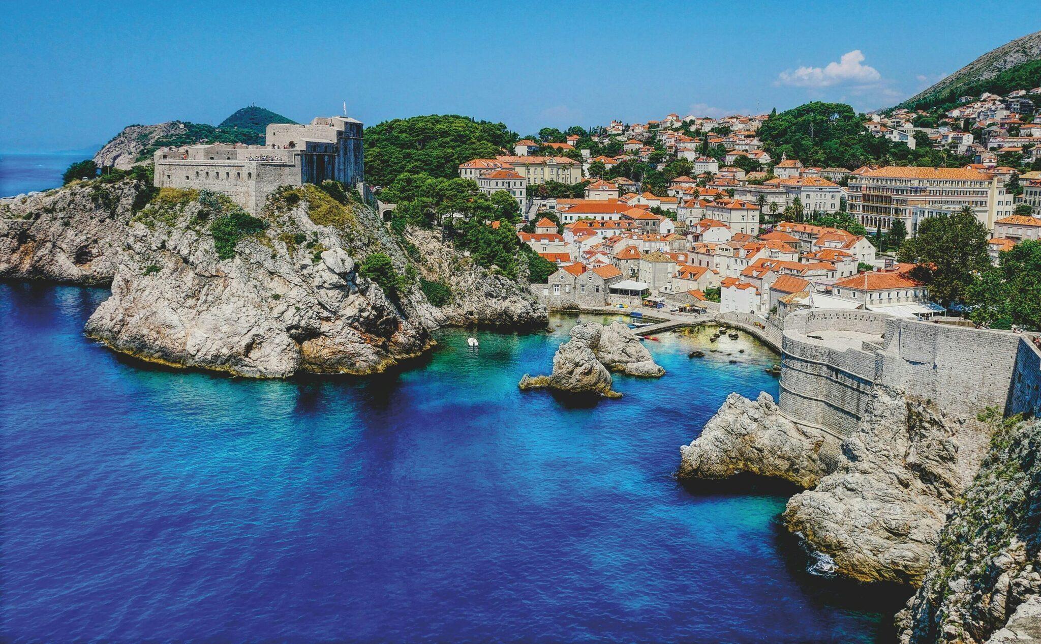 Vue panoramique d’une ville côtière médiévale avec fortification sur falaise rocheuse surplombant une baie turquoise