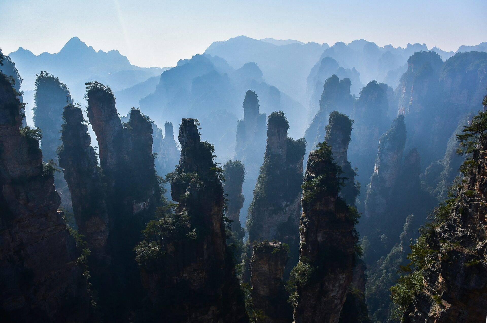 Spektakuläre Sandsteinformationen mit dichter Vegetation in einem von blauem Dunst umhüllten Gebirgstal