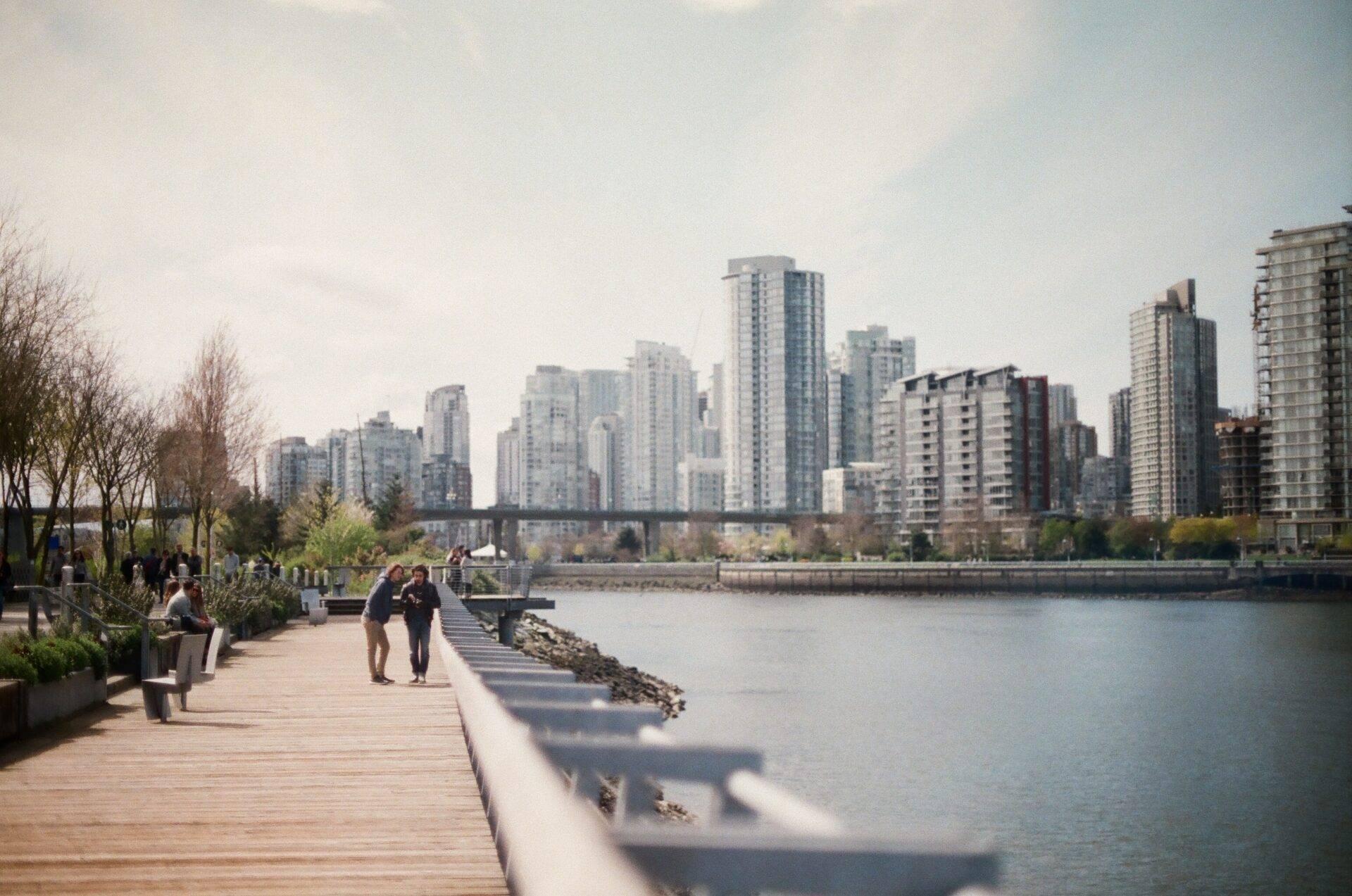 Une promenade en bois le long d’une rivière avec vue sur les gratte-ciel d’une grande ville canadienne