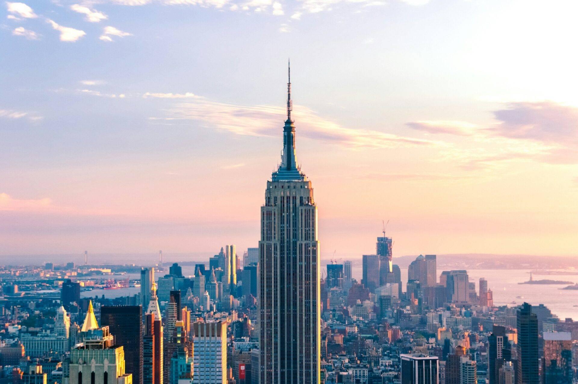 Vista panoramica su un grattacielo iconico che domina un denso skyline urbano con il fiume sullo sfondo al tramonto
