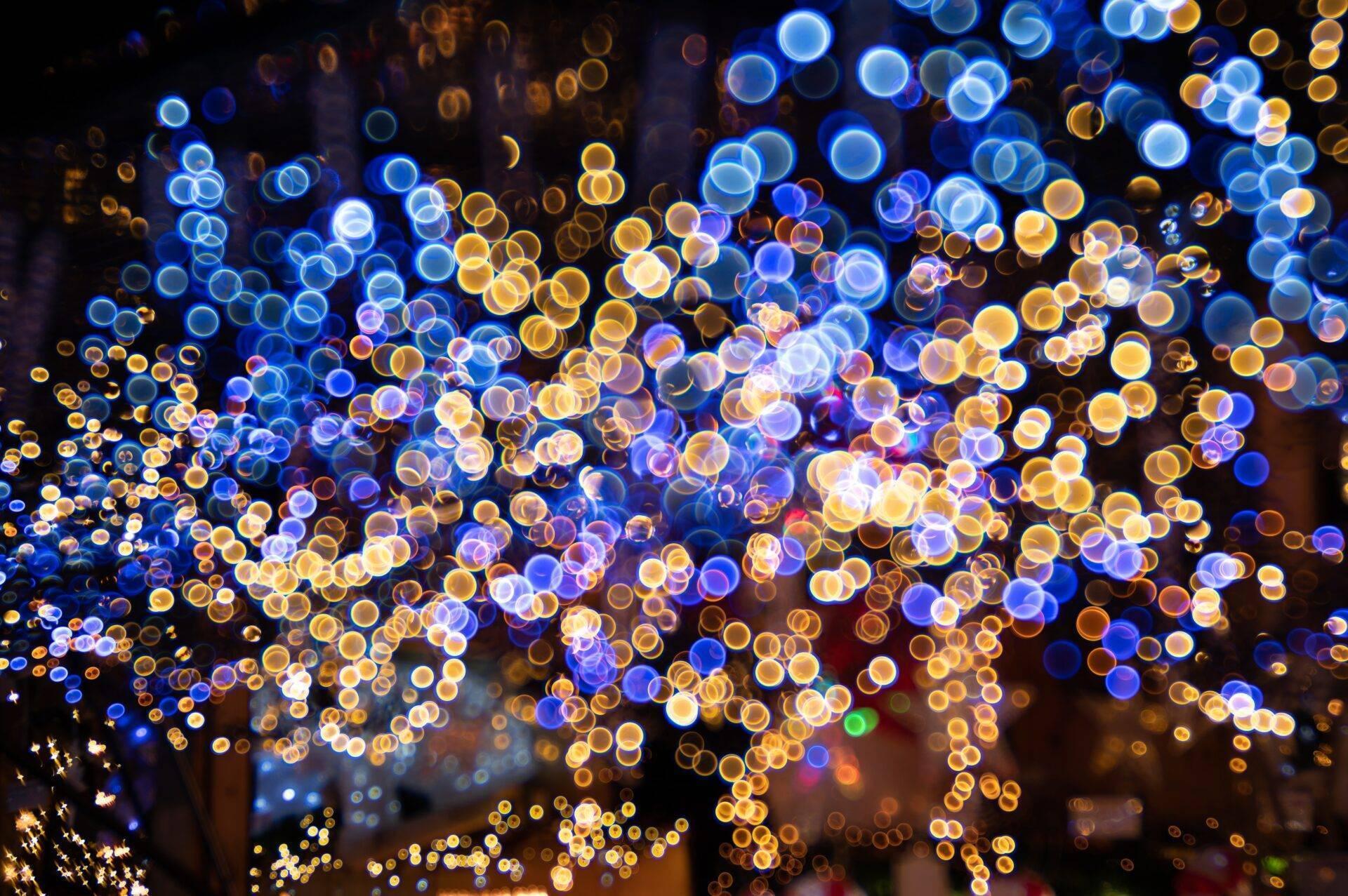 Décoration lumineuse festive avec des centaines de boules brillantes bleues, dorées et blanches suspendues dans la nuit