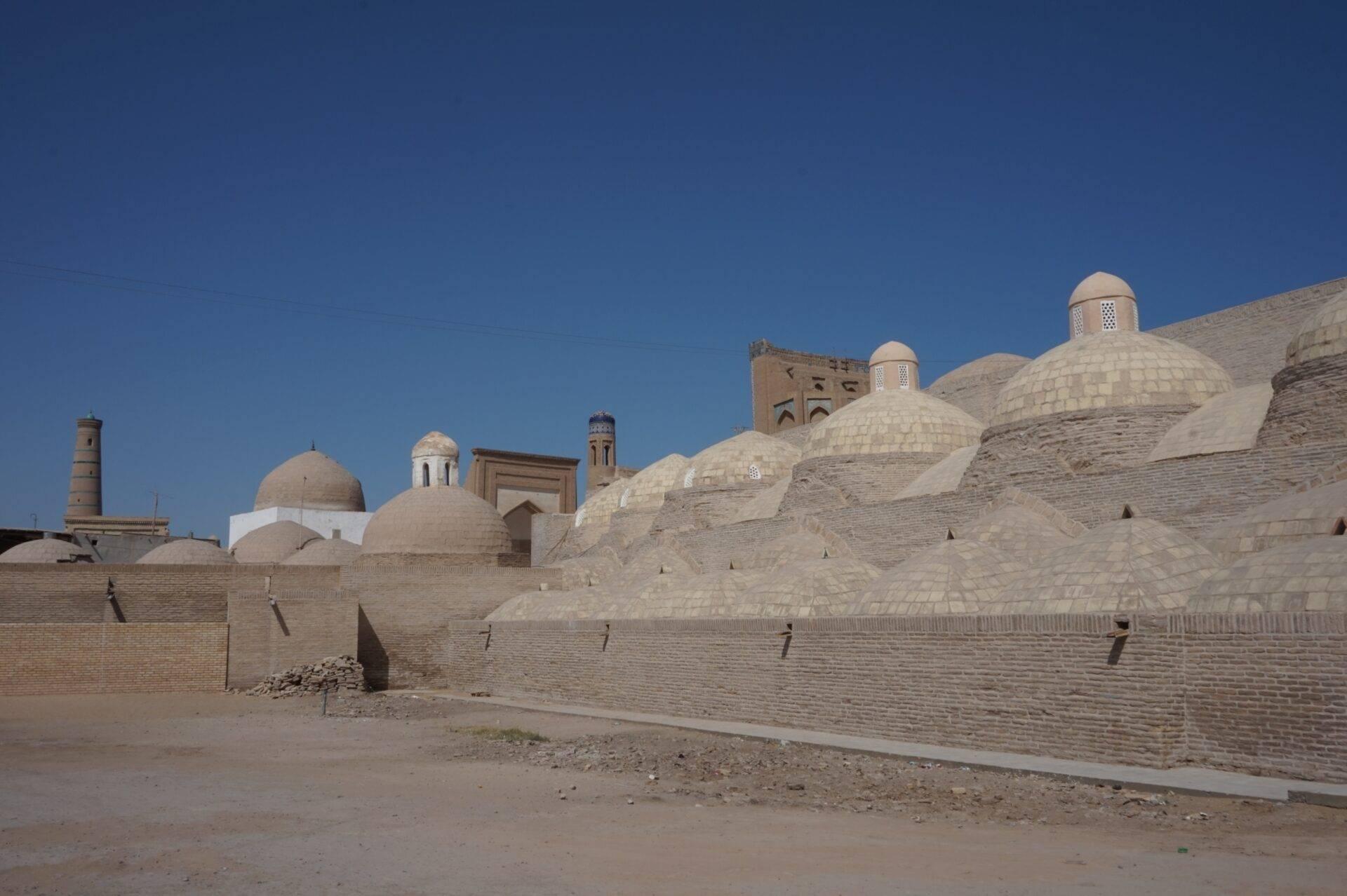 Vue d’ensemble d’une médina historique avec dômes blanchis et murailles en brique sous ciel bleu dégagé