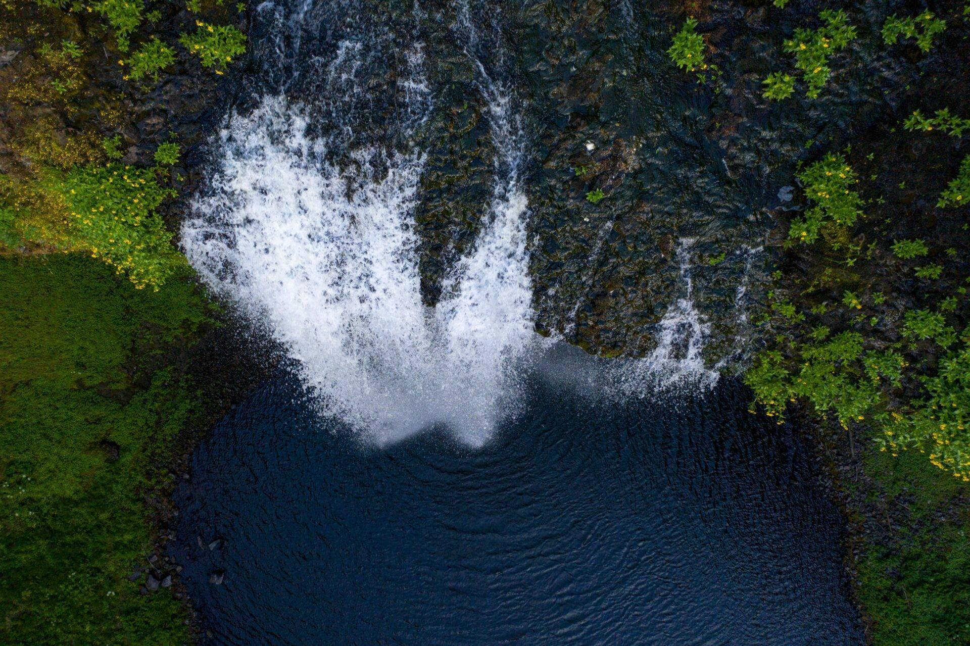 Vista aerea di una cascata impetuosa che scorre in una vasca rocciosa circondata da lussureggiante vegetazione verde