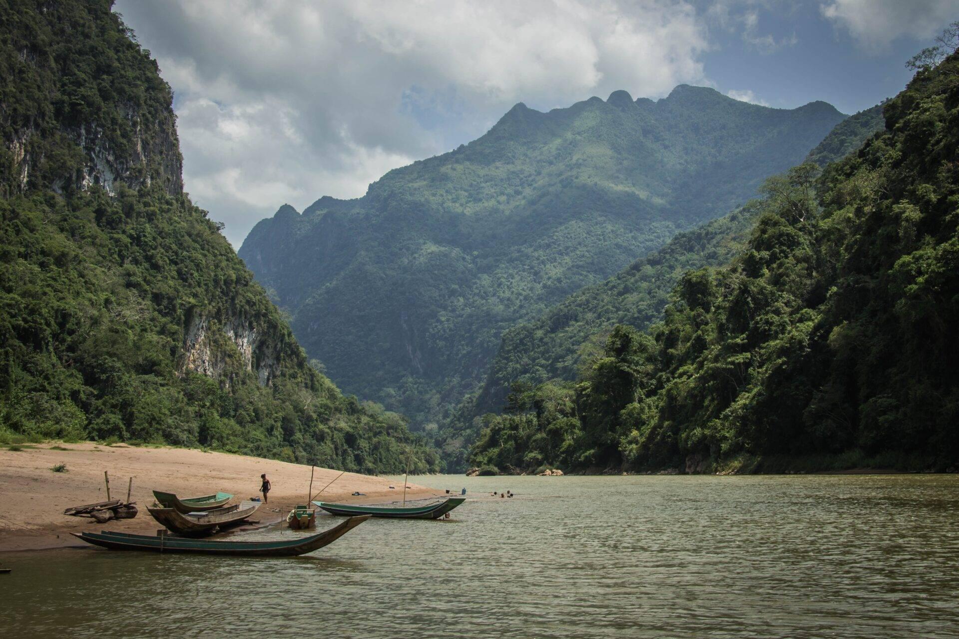 Voyageur contemplant le Mékong au Laos, pirogue traditionnelle au premier plan