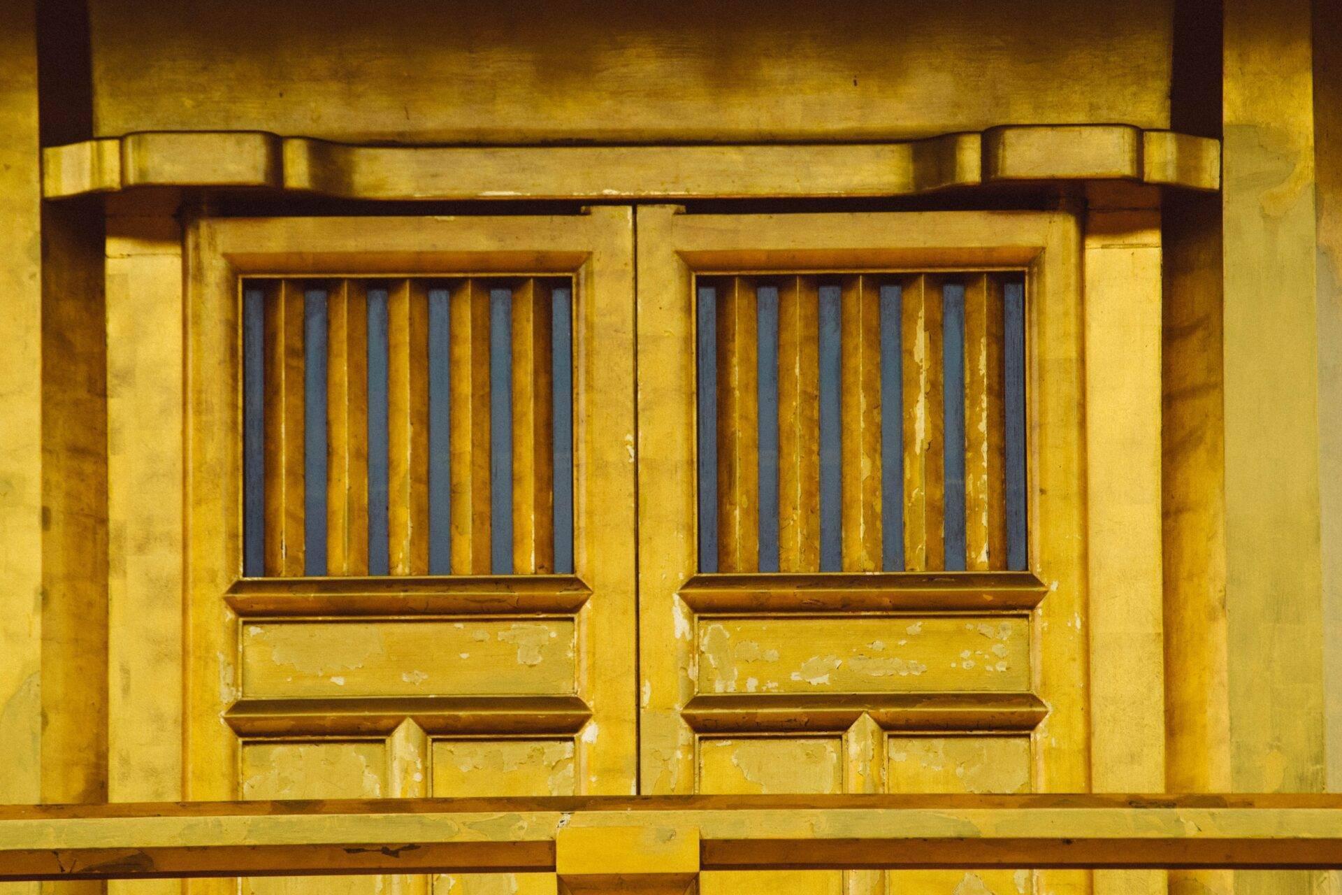 Façade jaune colonial avec deux portes à barreaux métalliques et panneaux peints, architecture historique asiatique