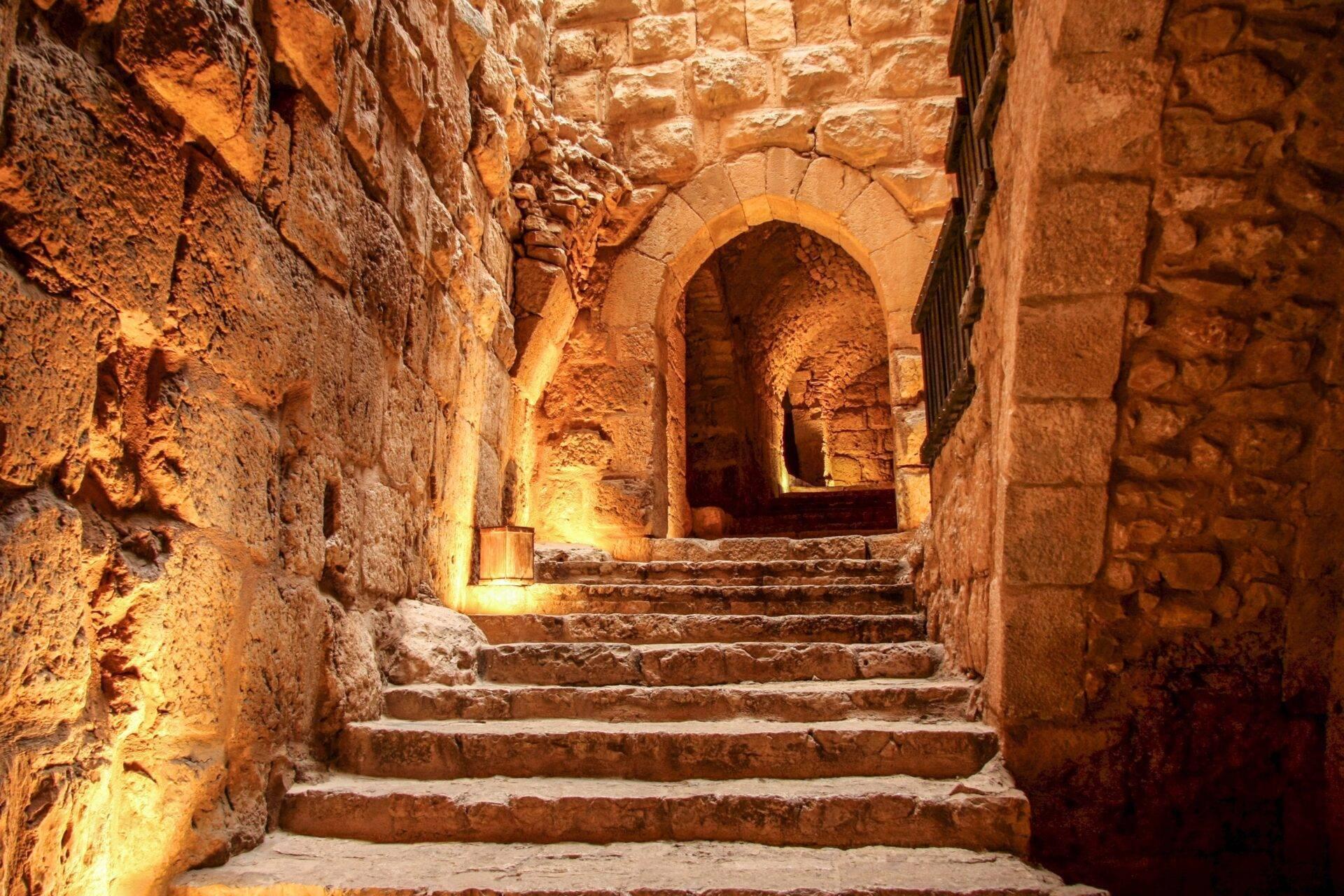 Scalinata in pietra illuminata che conduce a un arco a volta in un’antica fortezza mediorientale