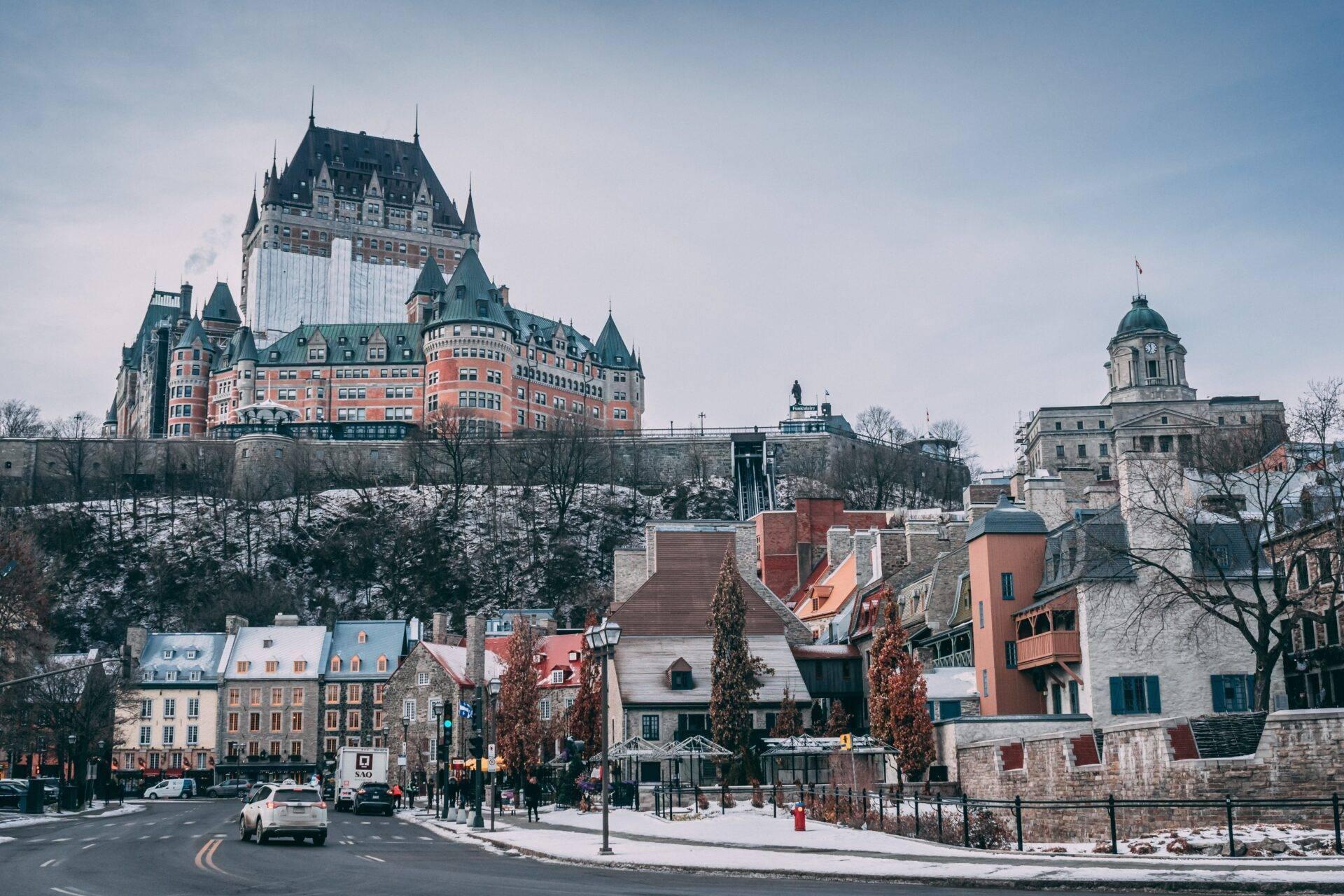 Vue hivernale d’un château médiéval en pierre rouge dominant une ville historique avec églises et demeures anciennes
