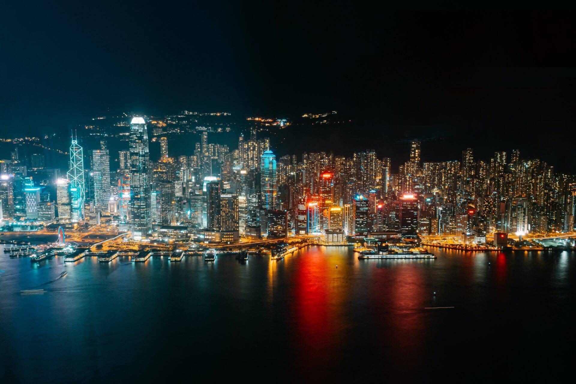 Skyline nocturne d’une métropole côtière illuminée avec gratte-ciel reflétés sur l’eau