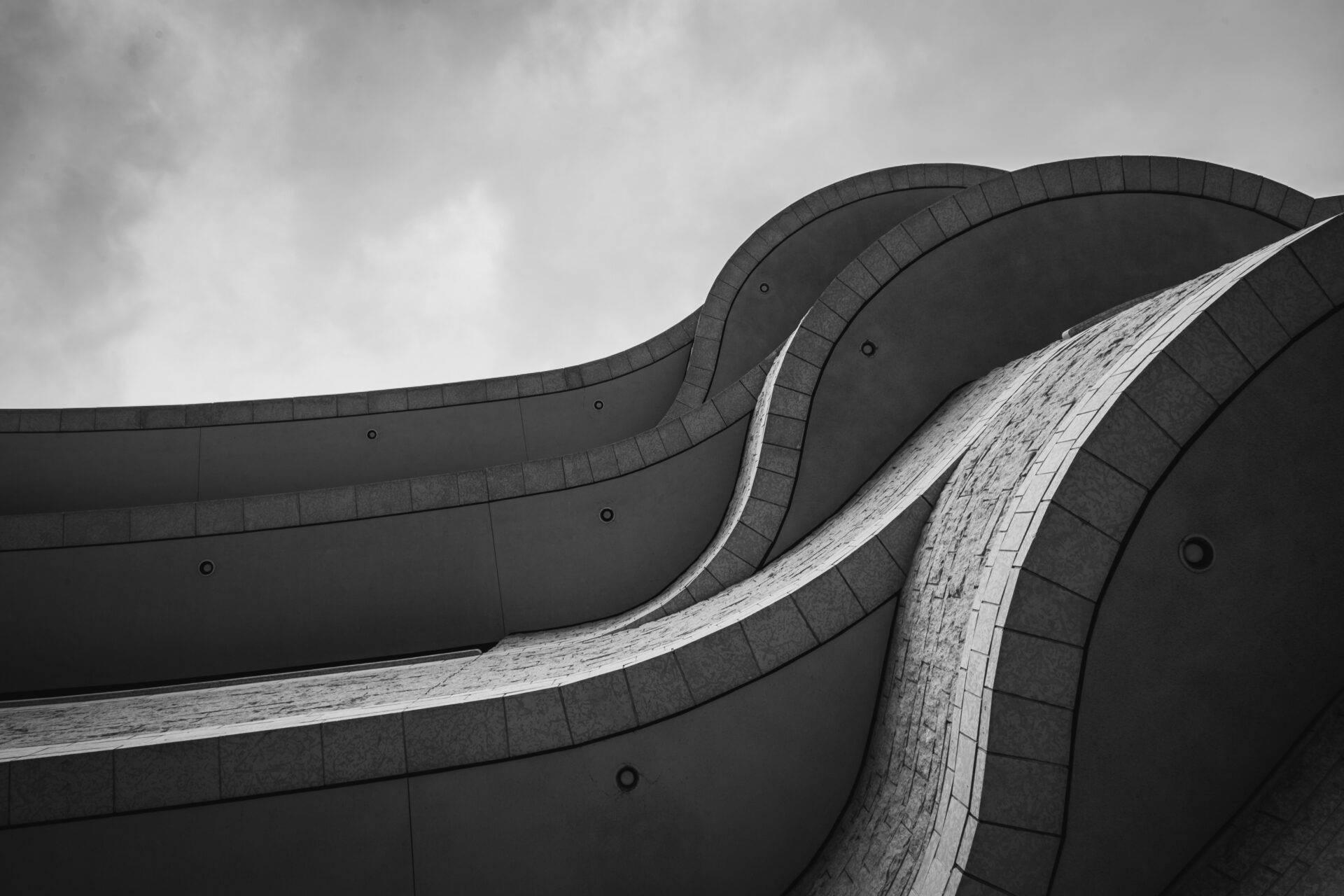 Détail architectural en noir et blanc d’un bâtiment moderne aux courbes ondulantes et revêtement de tuiles
