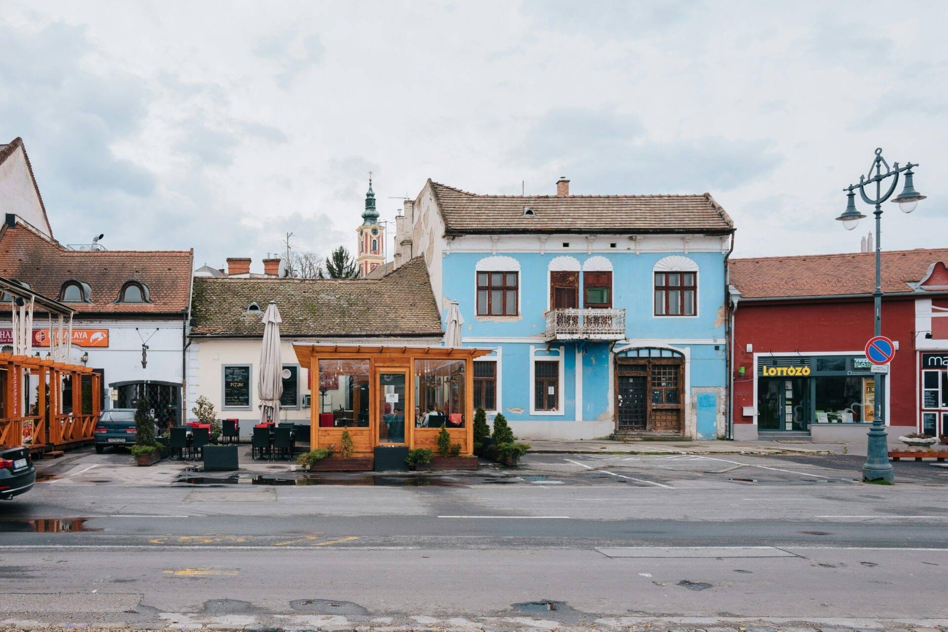 Una piazza di villaggio dell’Europa centrale con case colorate dalle facciate blu e bianche e una chiesa sullo sfondo