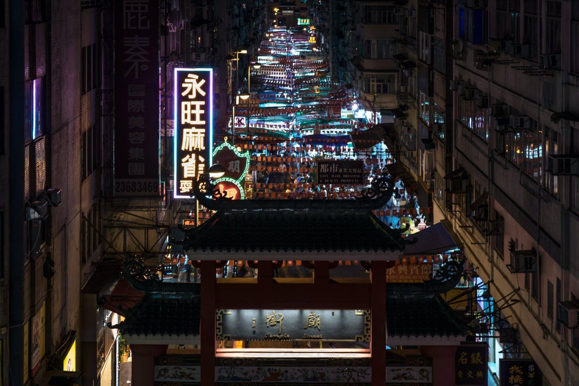 Une rue commerçante animée la nuit avec temple asiatique illuminé et néons colorés en arrière-plan