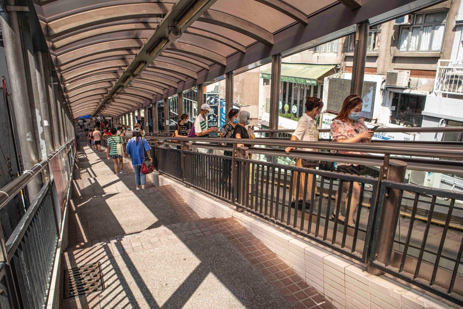 Passage couvert animé avec commerces, clients et piétons sous une verrière métallique, architecture urbaine typique asiatique