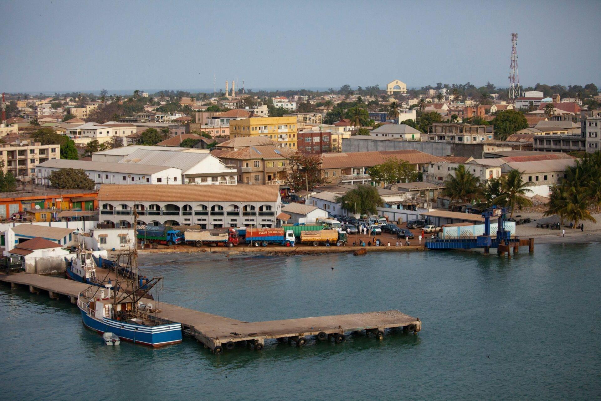 Vista panoramica di un porto fluviale africano con barche, magazzini colorati e la città sullo sfondo