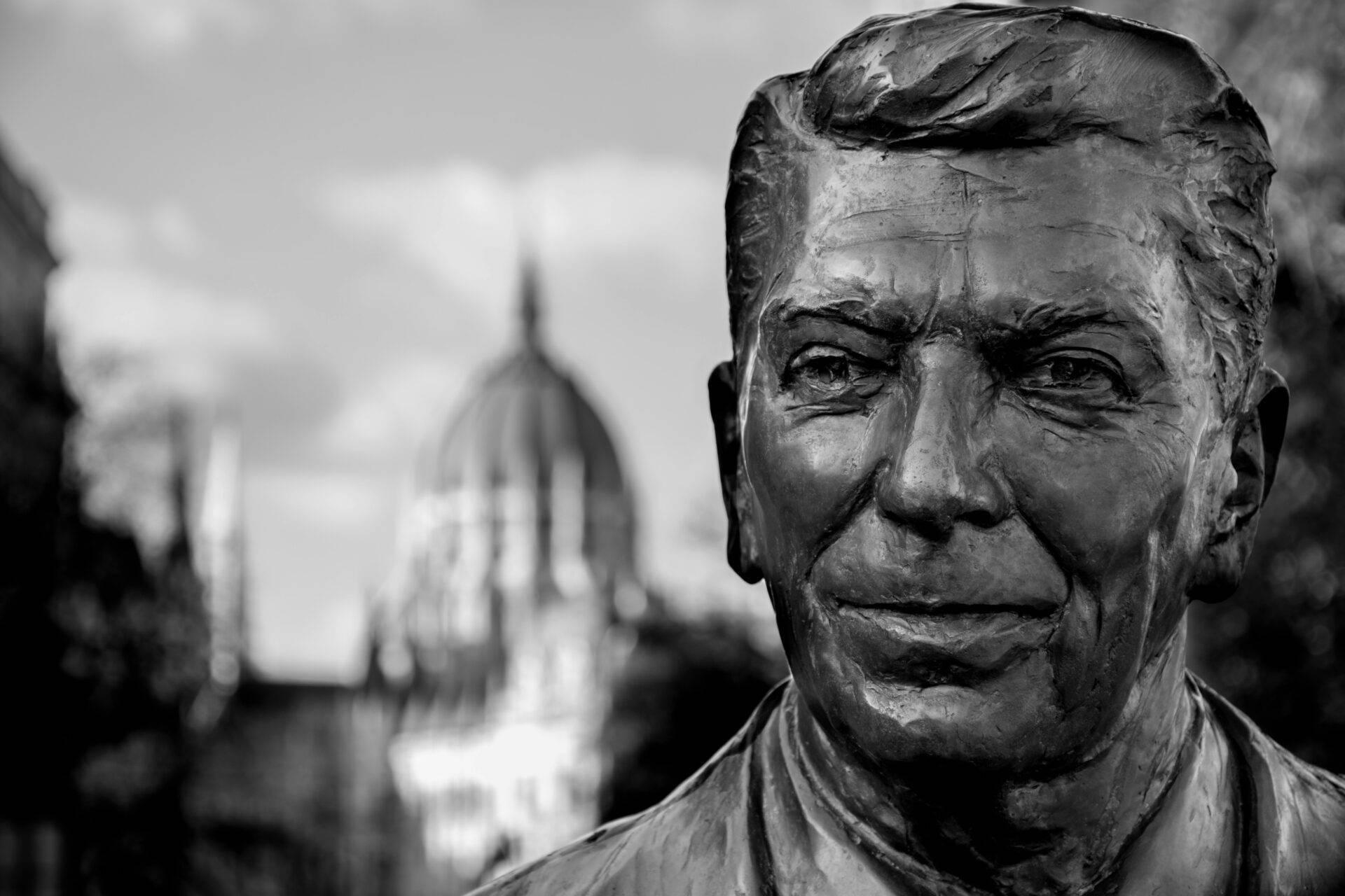 Statua in bronzo di un uomo con un edificio religioso a cupola sullo sfondo, atmosfera urbana invernale
