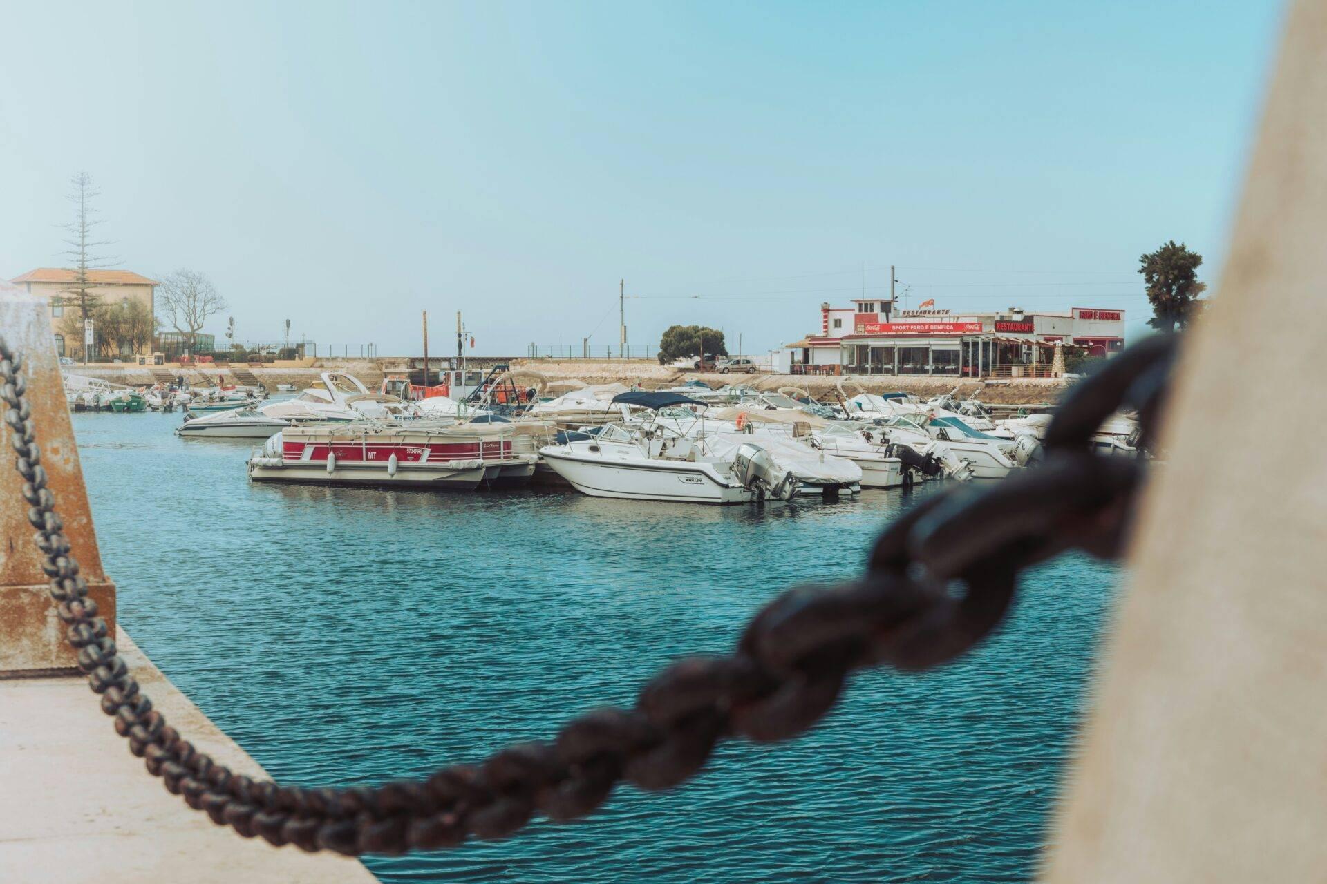 Un piccolo porto mediterraneo con barche da pesca e un ristorante costiero sotto un cielo sereno