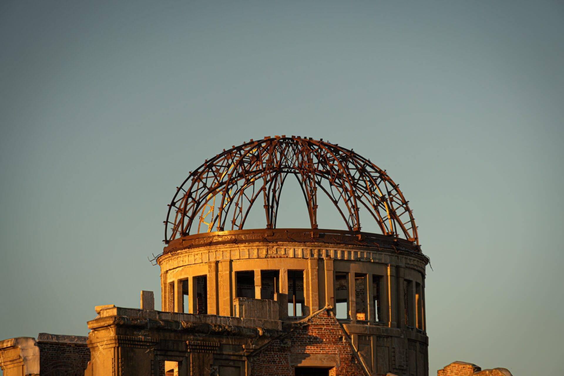 Dôme mémoriel en ruines avec structure métallique distinctive sous ciel clair, symbole historique architectural