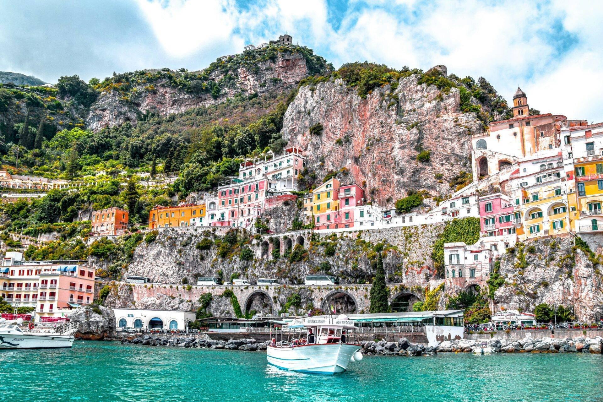 Un borgo costiero colorato aggrappato alle scogliere rocciose con barche ormeggiate nel Mediterraneo