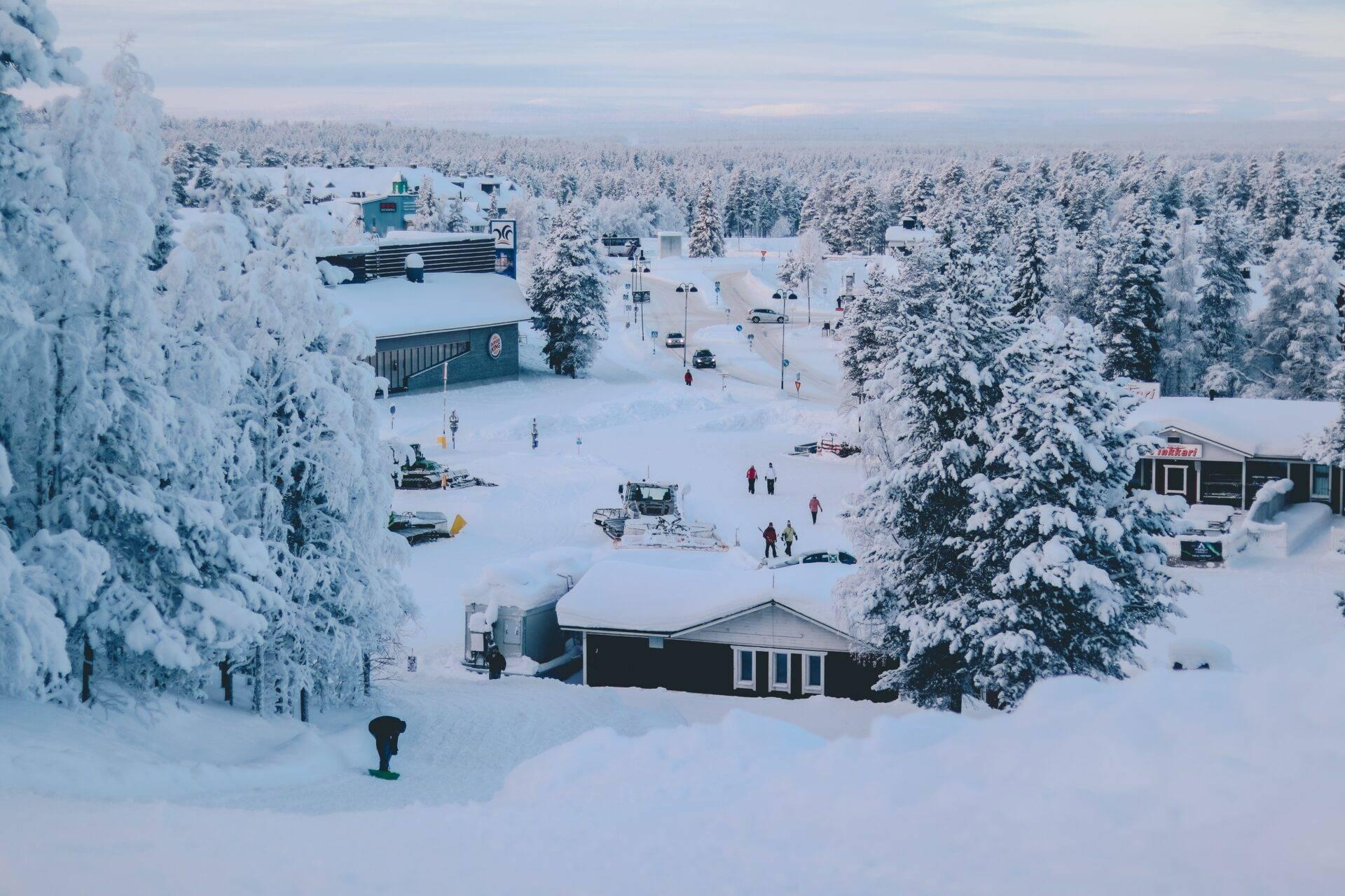 Vue aérienne d’une station de ski en Laponie avec chalets, pistes enneigées et forêt de sapins couverts de neige