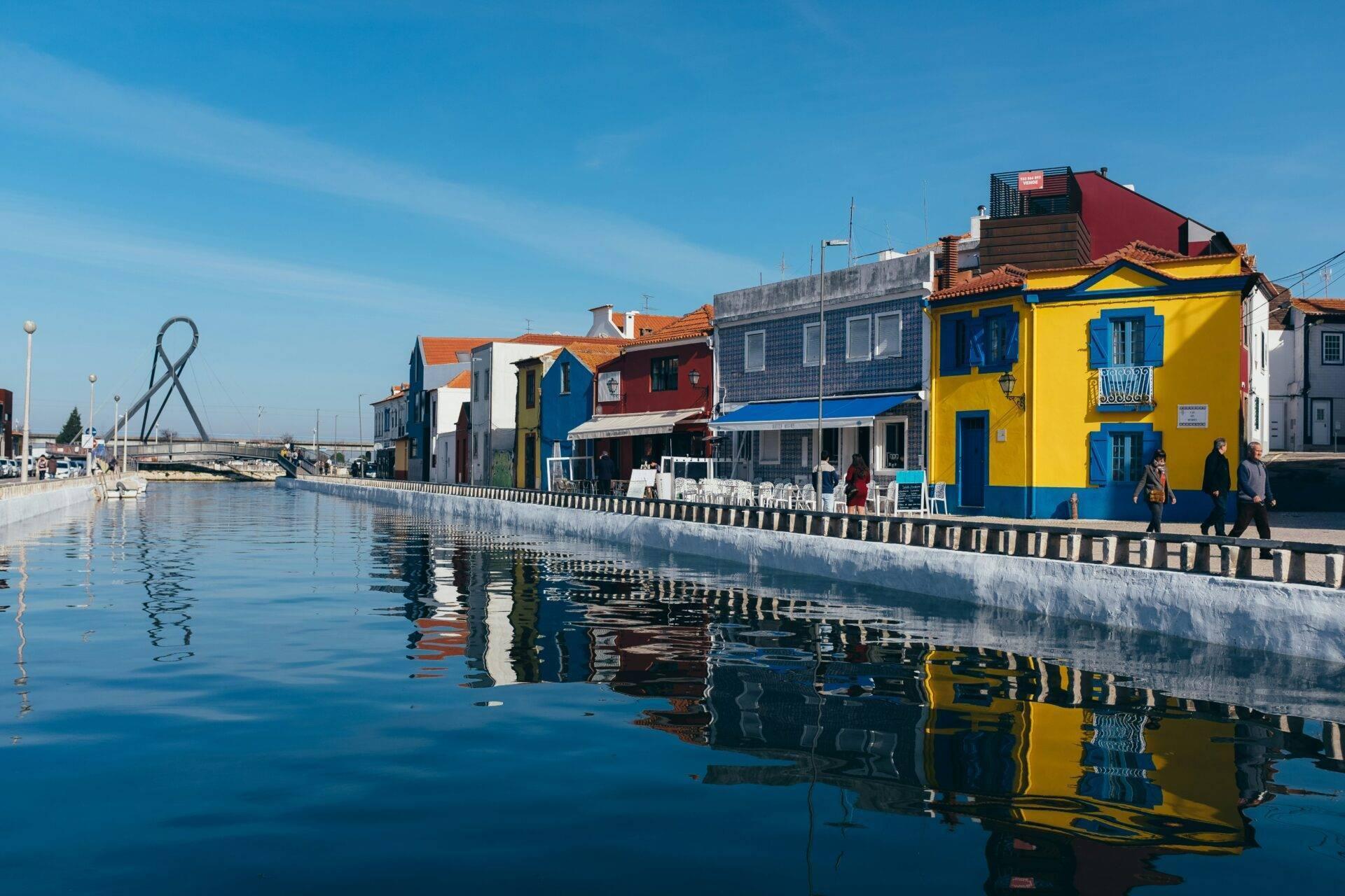 Case colorate che si riflettono in un canale tranquillo di una città costiera portoghese in una bella giornata di sole