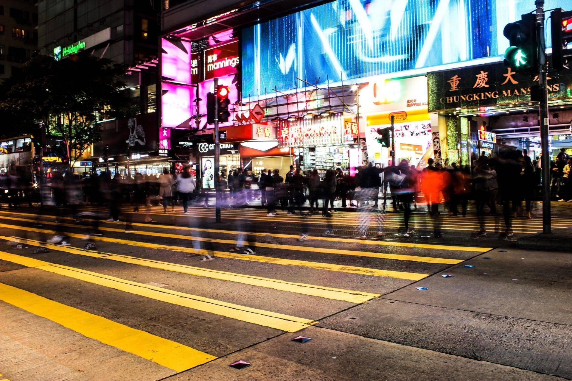Une rue commerçante animée de nuit avec enseignes lumineuses, passages piétons et foules de touristes et habitants