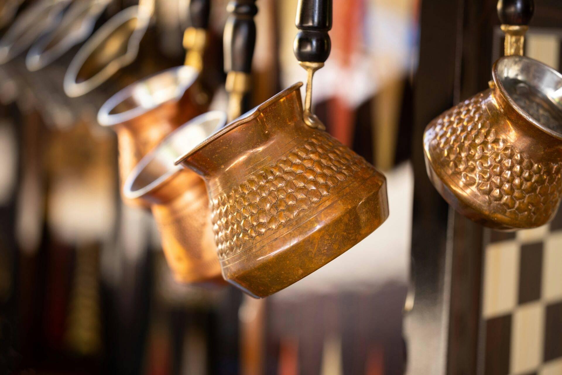 Brocche in rame martellato appese, artigianato tradizionale esposto in un mercato o bottega artigianale