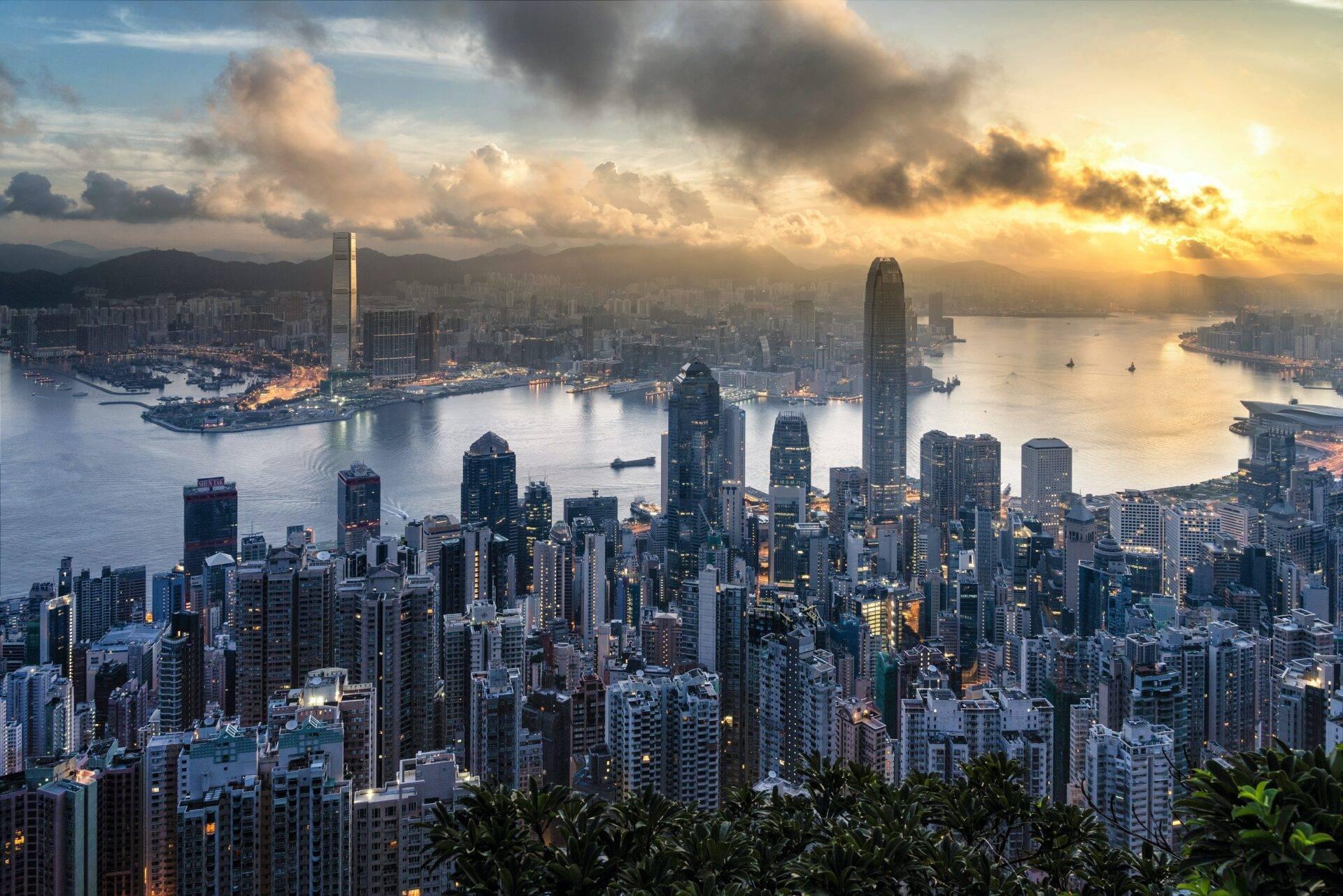 Vue aérienne d’une métropole asiatique au coucher de soleil avec gratte-ciel, baie et montagnes