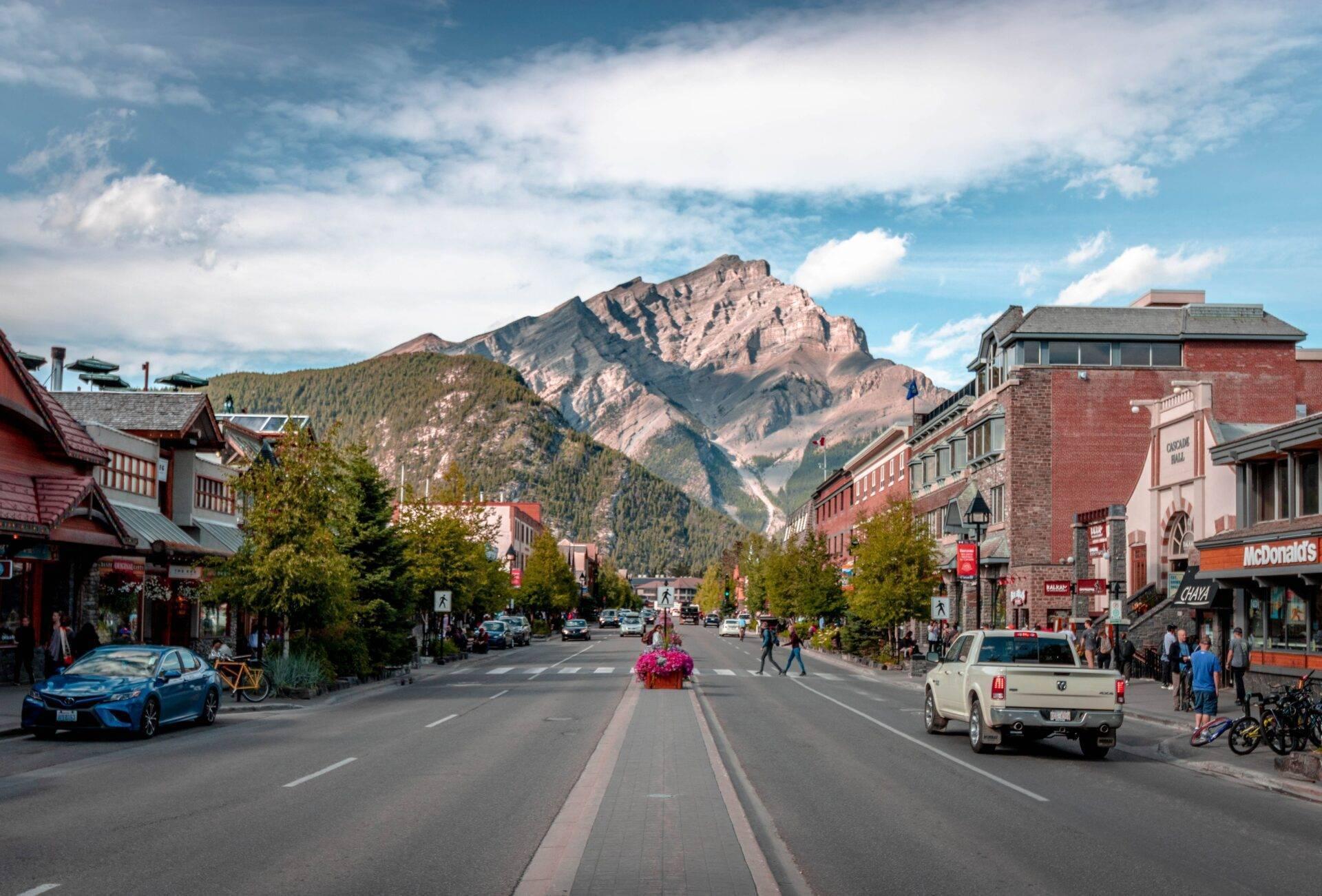 Une rue commerçante animée d’une petite ville de montagne canadienne avec pics rocheux en arrière-plan