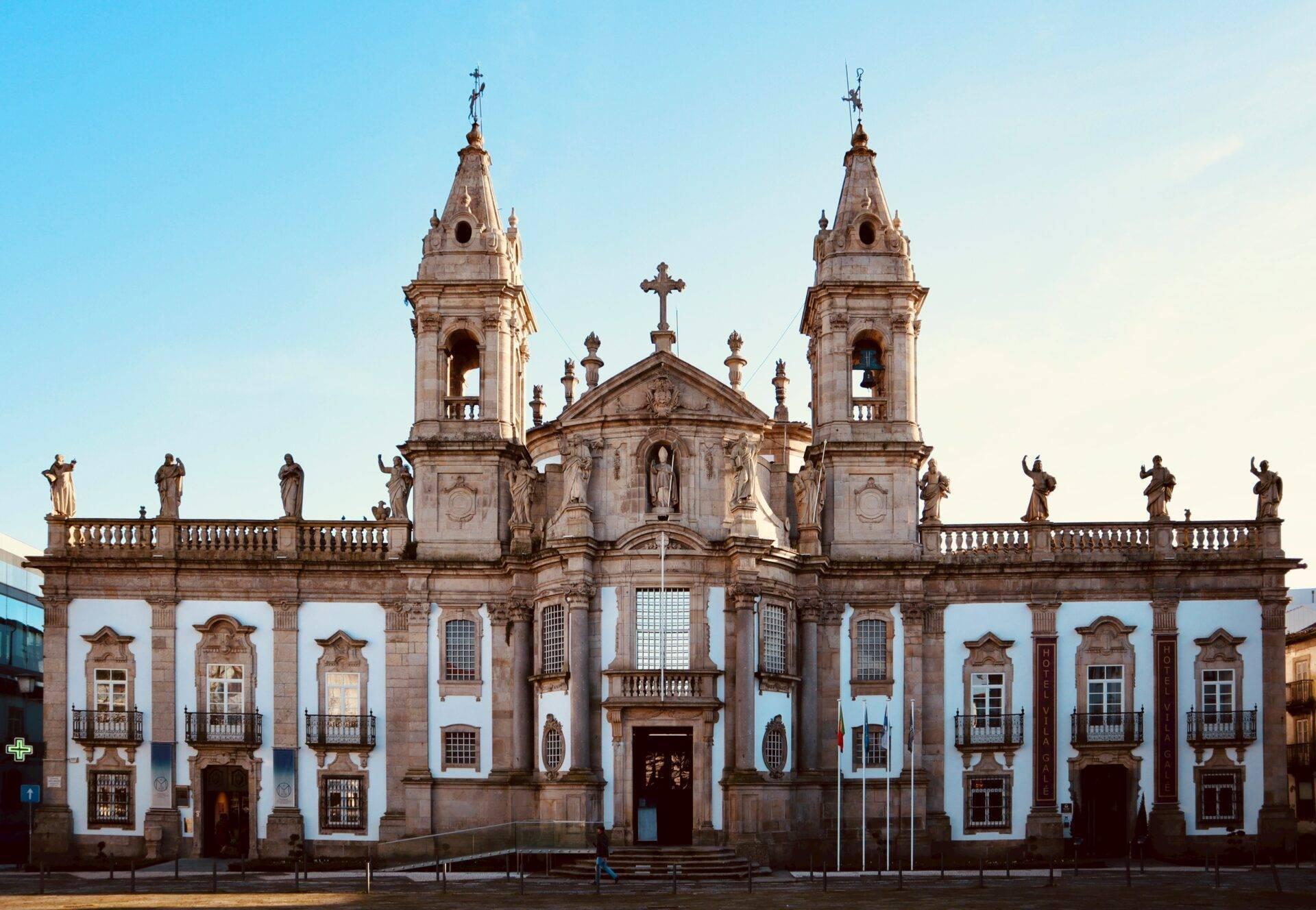 Facciata bianca e dorata di una chiesa coloniale barocca con due campanili gemelli e statue religiose