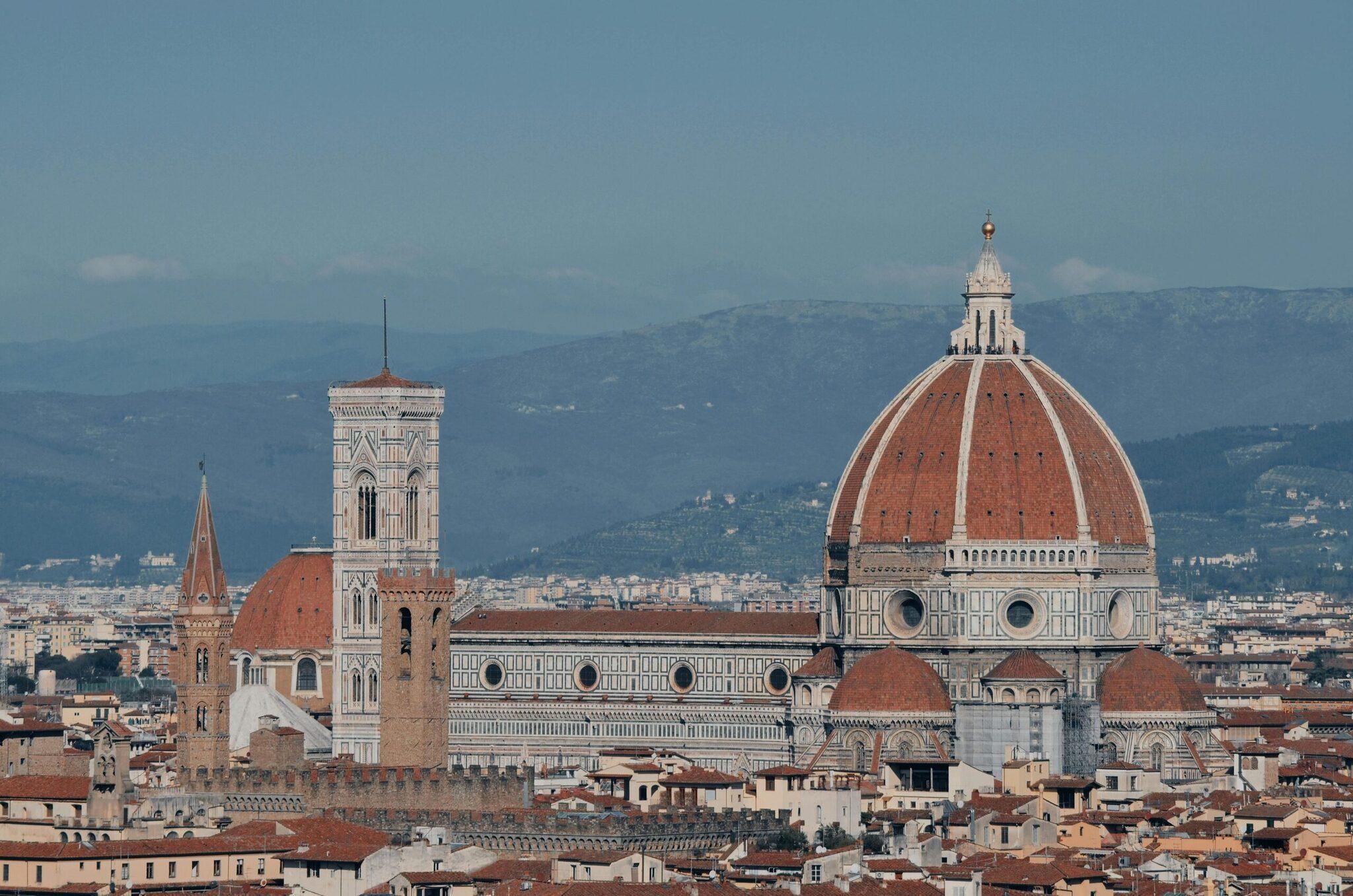 Vue panoramique sur la cathédrale aux dôme terracotta et campanile blanc ornementé dominant la ville toscane
