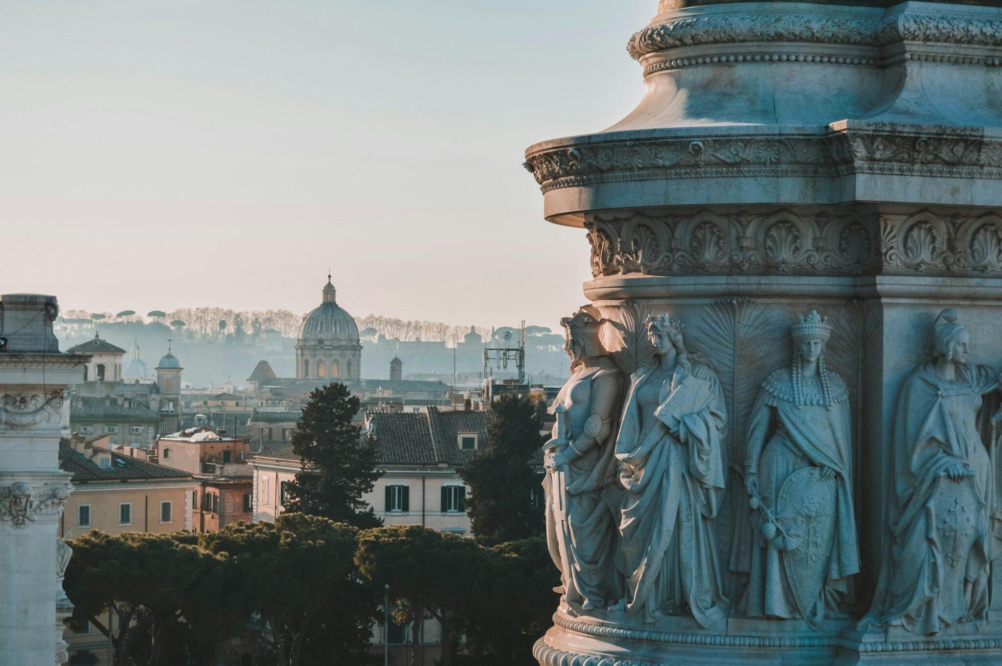 Vue panoramique de Rome avec statues classiques en premier plan et dôme de basilique au loin dans le paysage urbain