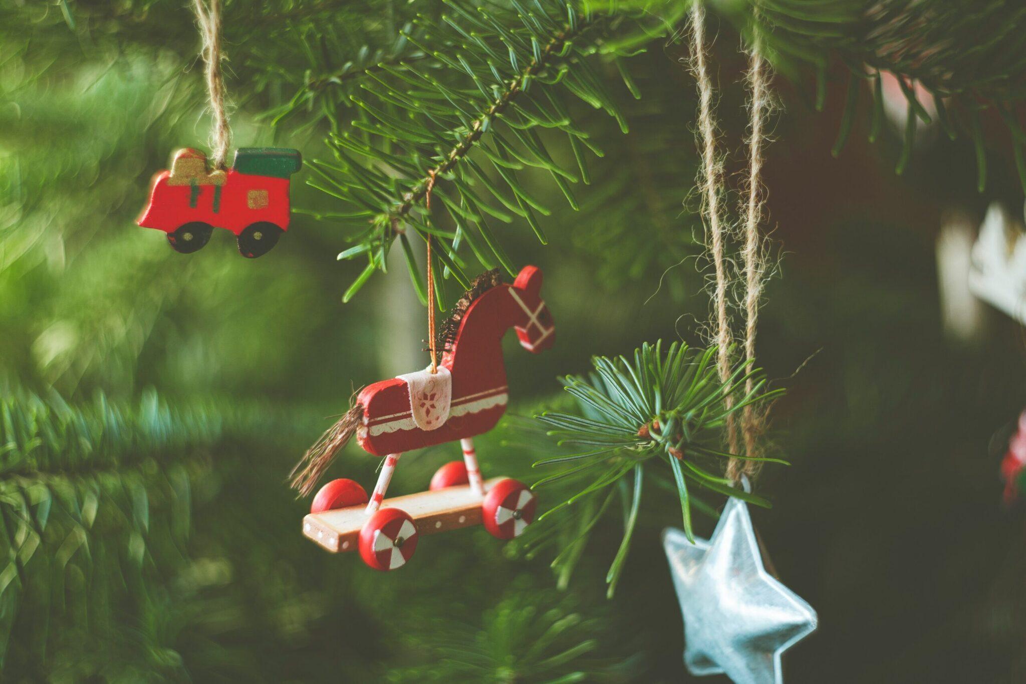 Red Christmas ornaments hanging from green fir branches, creating a warm festive mood