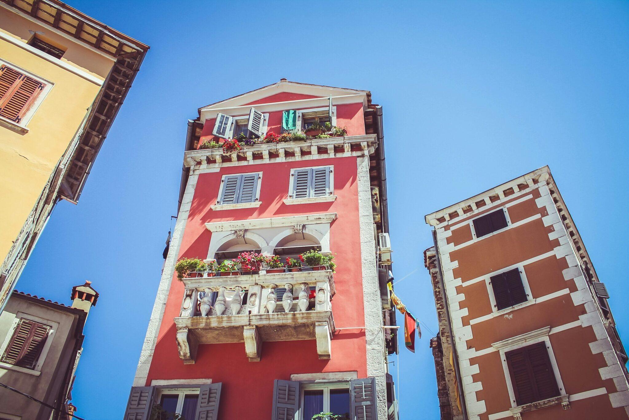 Façades colorées de bâtiments méditerranéens avec balcons fleuris sous ciel bleu dégagé