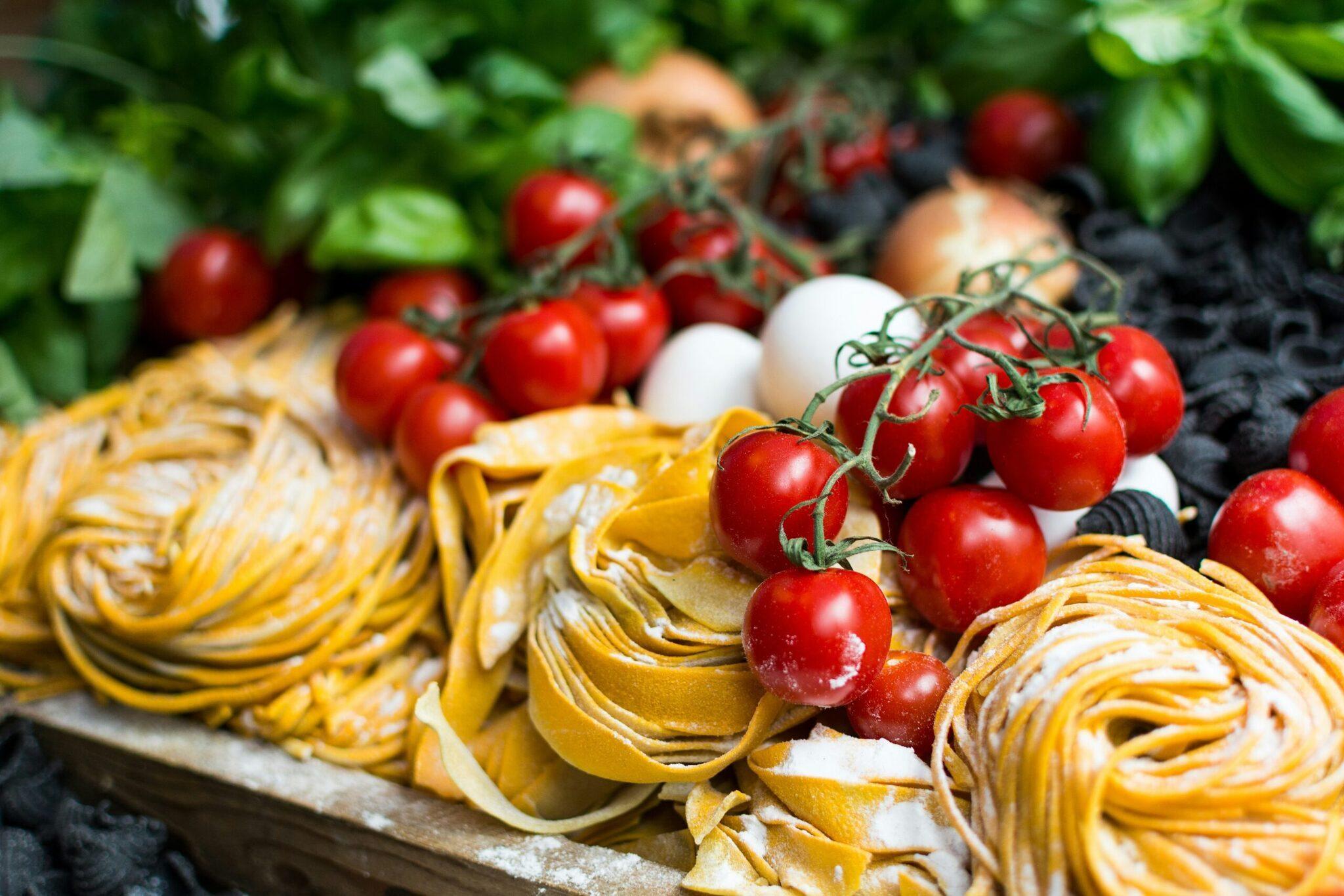 Étalage coloré de pâtes fraîches et tomates cerises sur un marché méditerranéen typique