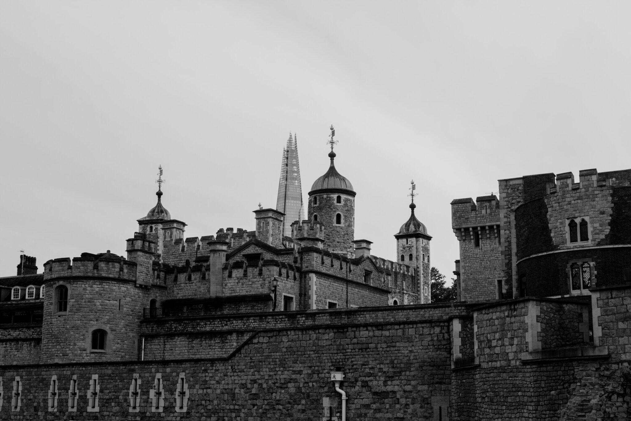 Mittelalterliche Steinburg mit Zinnen und Kuppeln, schwarz-weiß fotografiert unter bewölktem Himmel