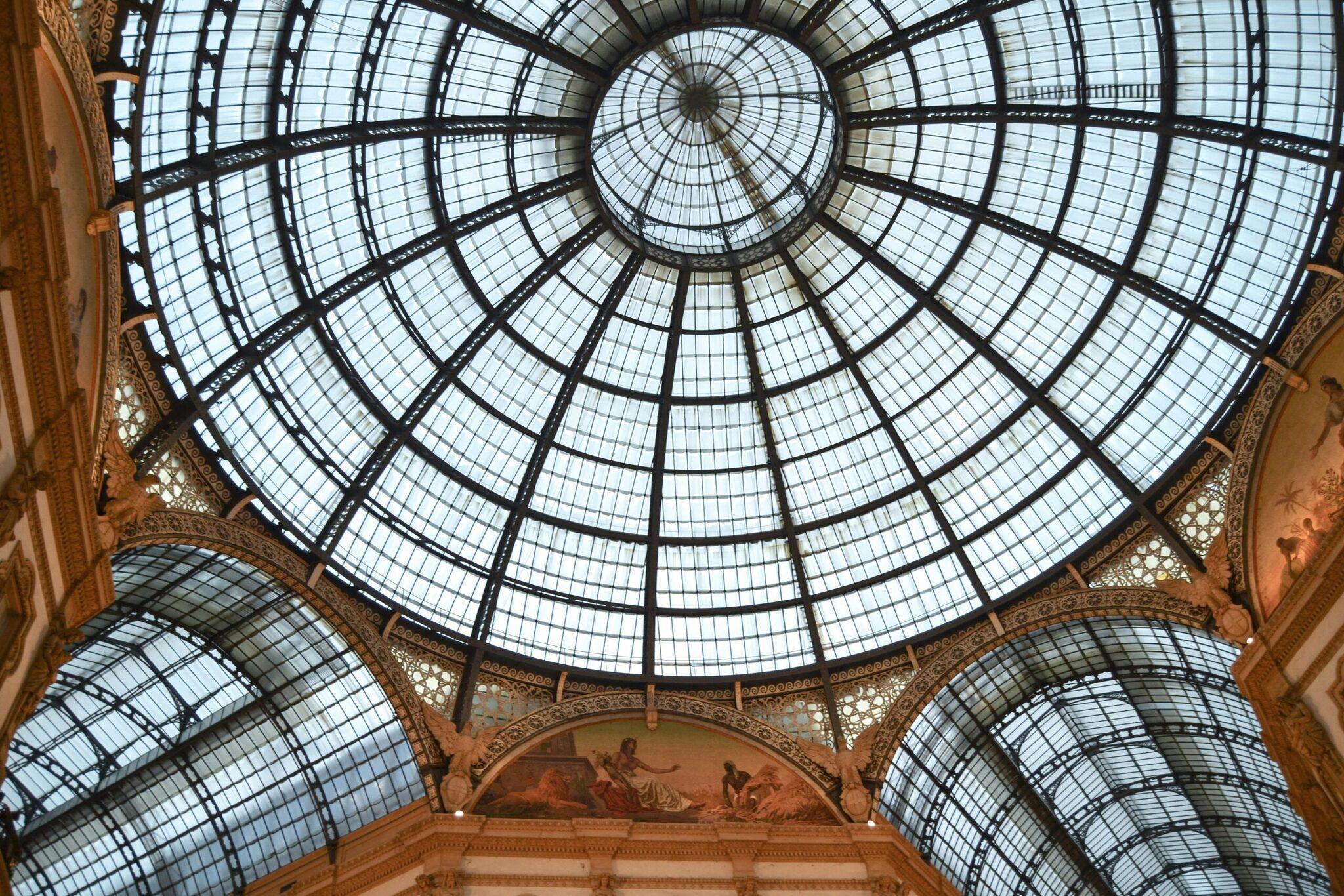 Plafond en verrière géométrique d’une galerie marchande historique avec ornementations dorées et fresques murales