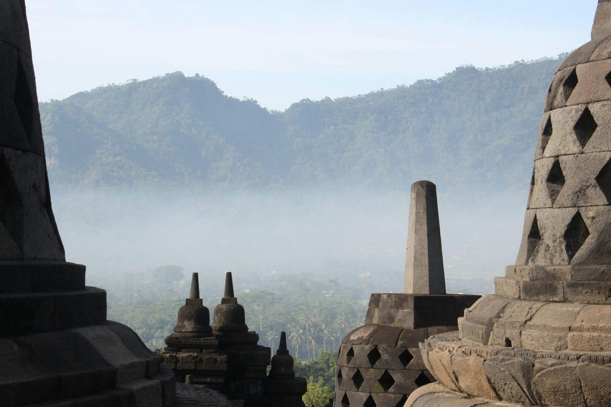 Vue depuis un temple bouddhiste sur une vallée montagneuse brumée couverte de végétation tropicale dense