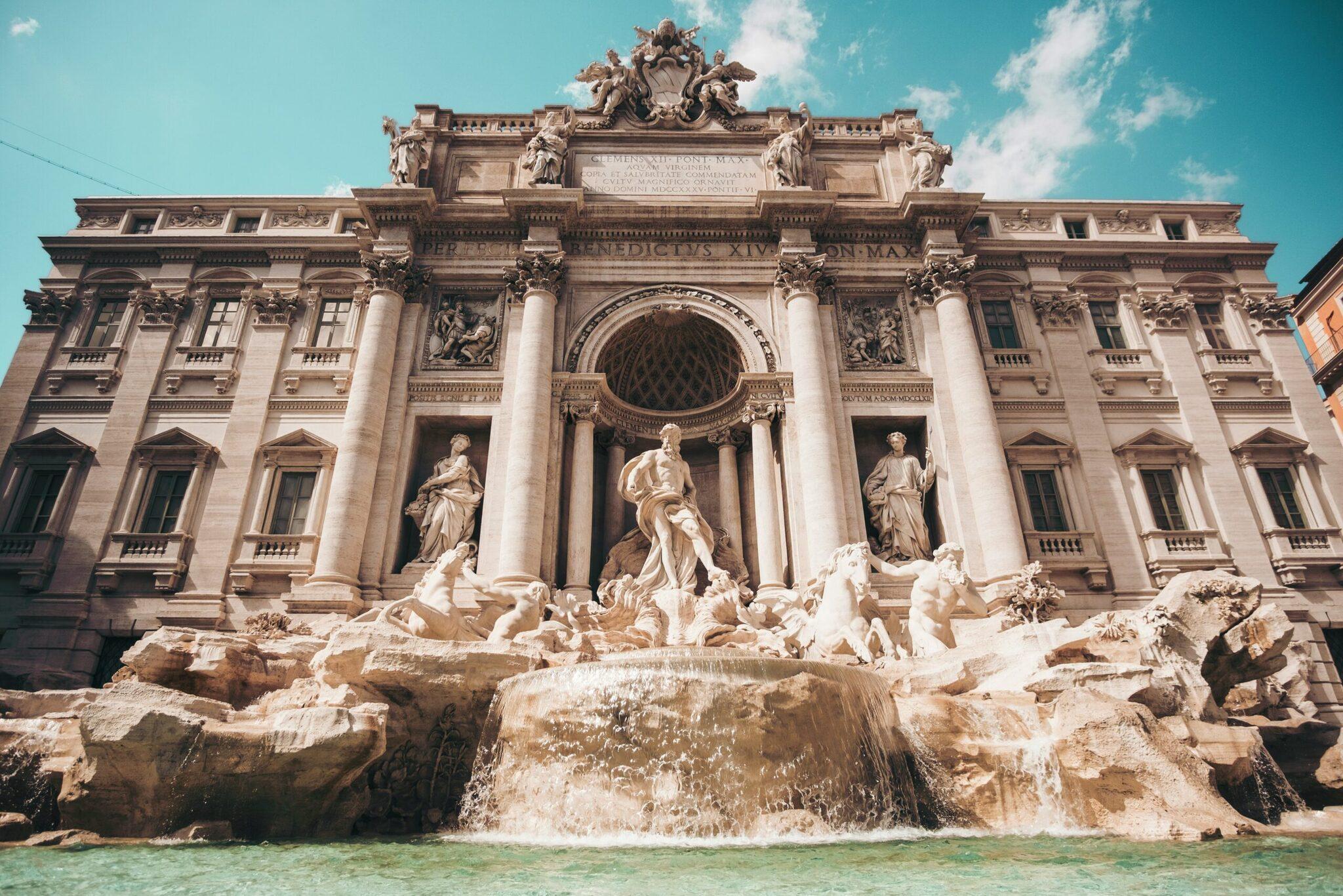La fontaine de Trevi avec son édifice baroque majestueux, ses sculptures et son bassin d’eau turquoise sous un ciel dégagé