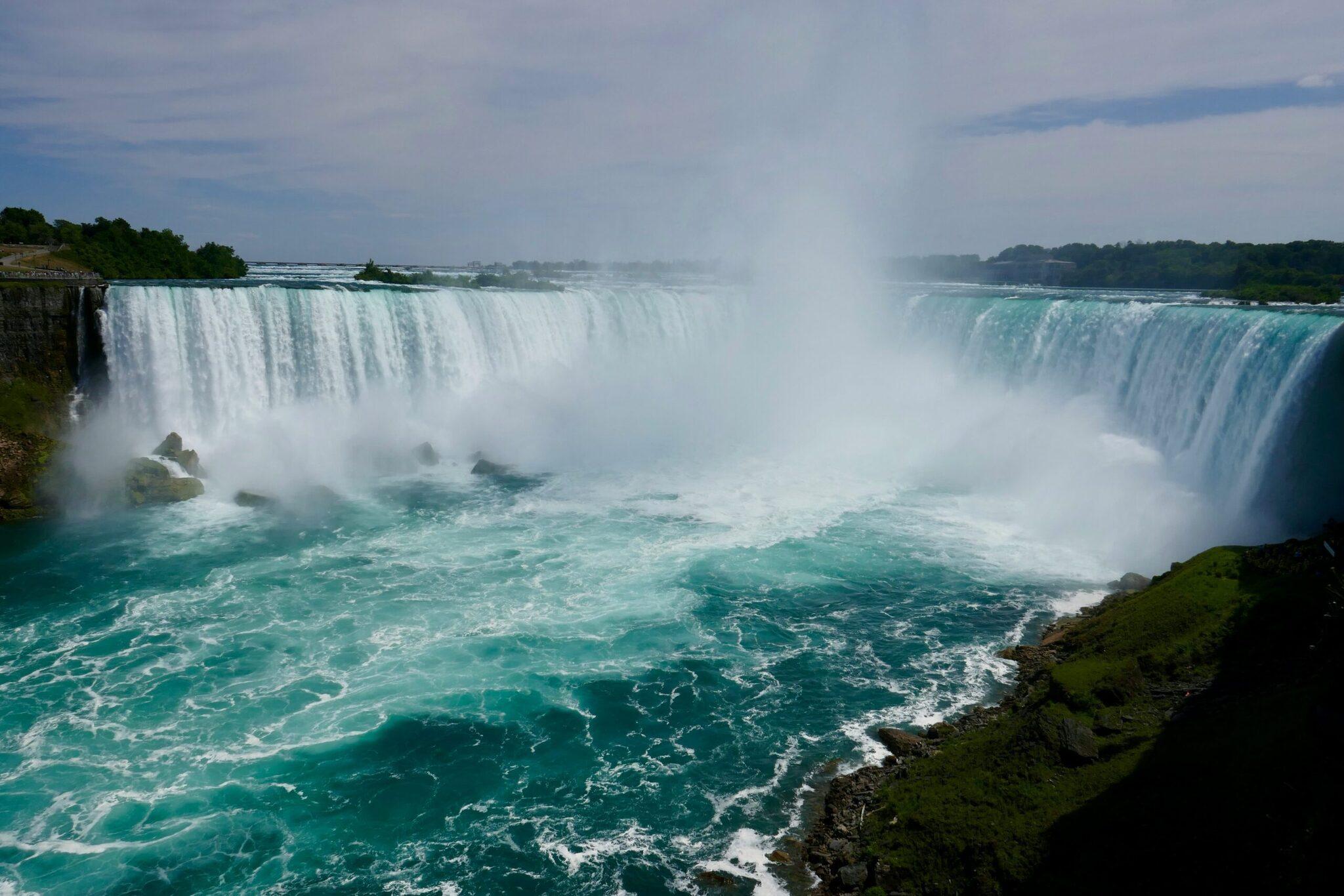 Imposantes chutes d’eau avec cascades écumantes et bassin turquoise entouré de falaises rocheuses verdoyantes