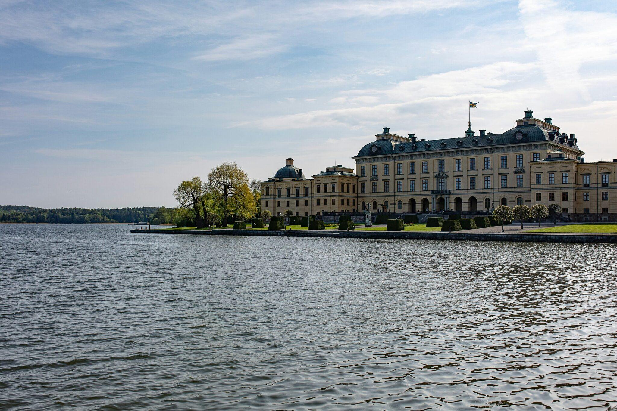 Un elegante palazzo in stile rococò dalle facciate gialle su un’isola lacustre, circondato dal verde e fotografato dall’acqua in una giornata limpida