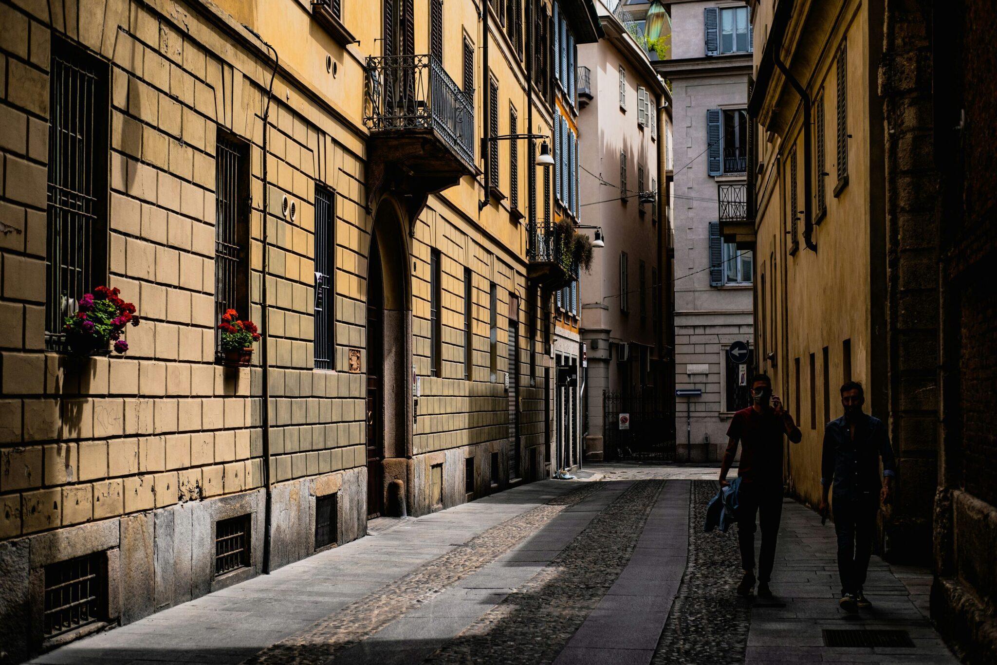 Une ruelle pavée étroite dans le centre historique d’une ville européenne, bordée de bâtiments en pierre de couleur ocre avec des façades classiques