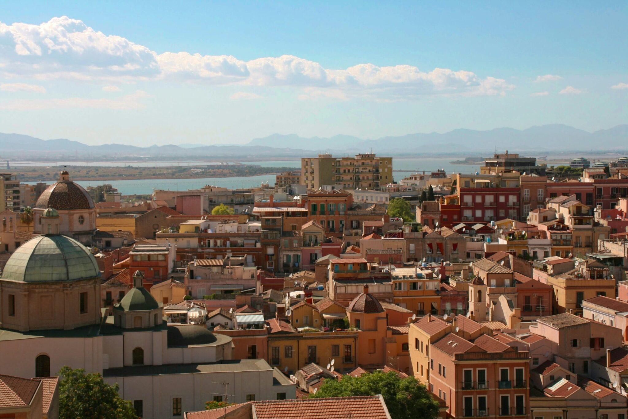Vue panoramique d’une ville côtière méditerranéenne avec église à dôme, architecture colorée et mer turquoise en arrière-plan